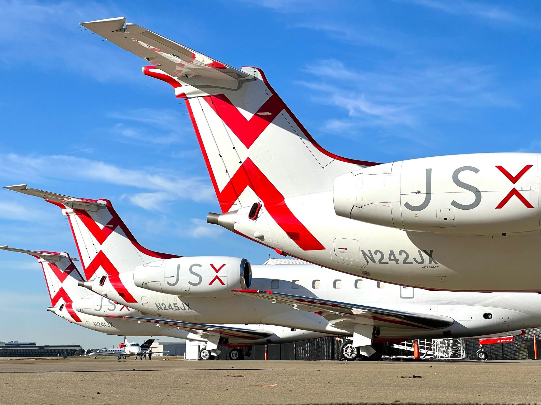 Several JSX Embraer aircraft parked on an airport apron.