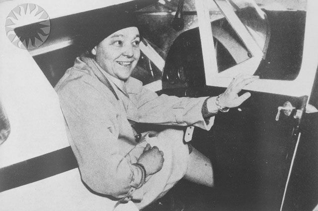 A photo of Phoebe Omlie sittin gin the cockpit of a small aircraft.