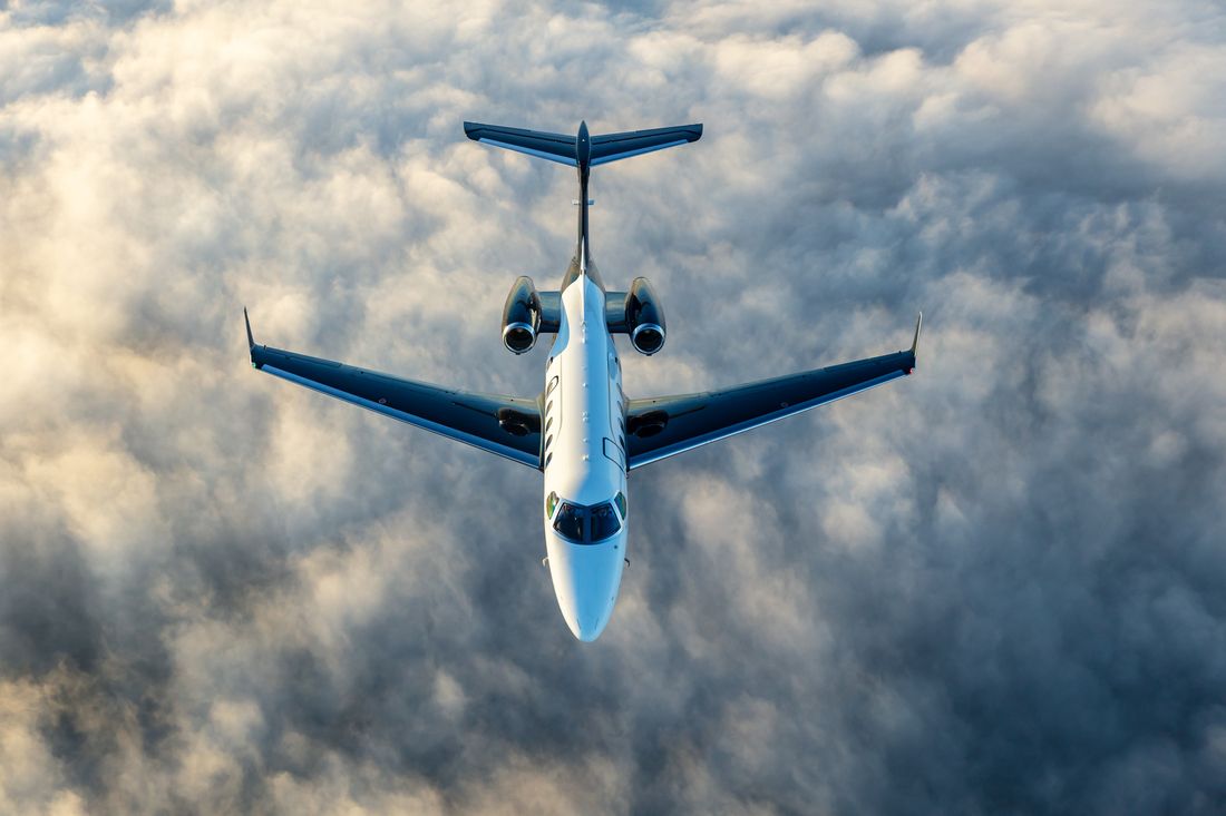 An Embraer Phenom 300 flying above the clouds.