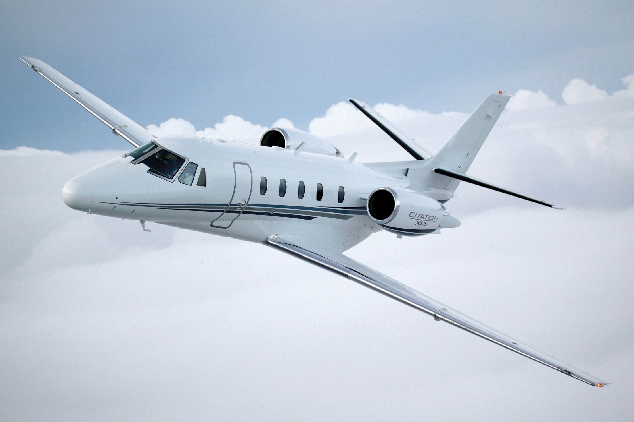 A Cessna Citation XLS flying above the clouds.