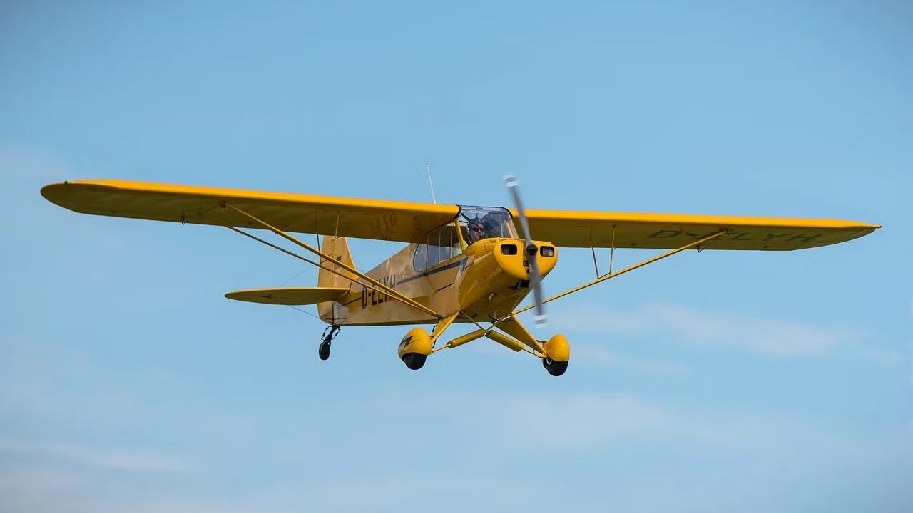 A Piper J-3 Cub flying in the sky.