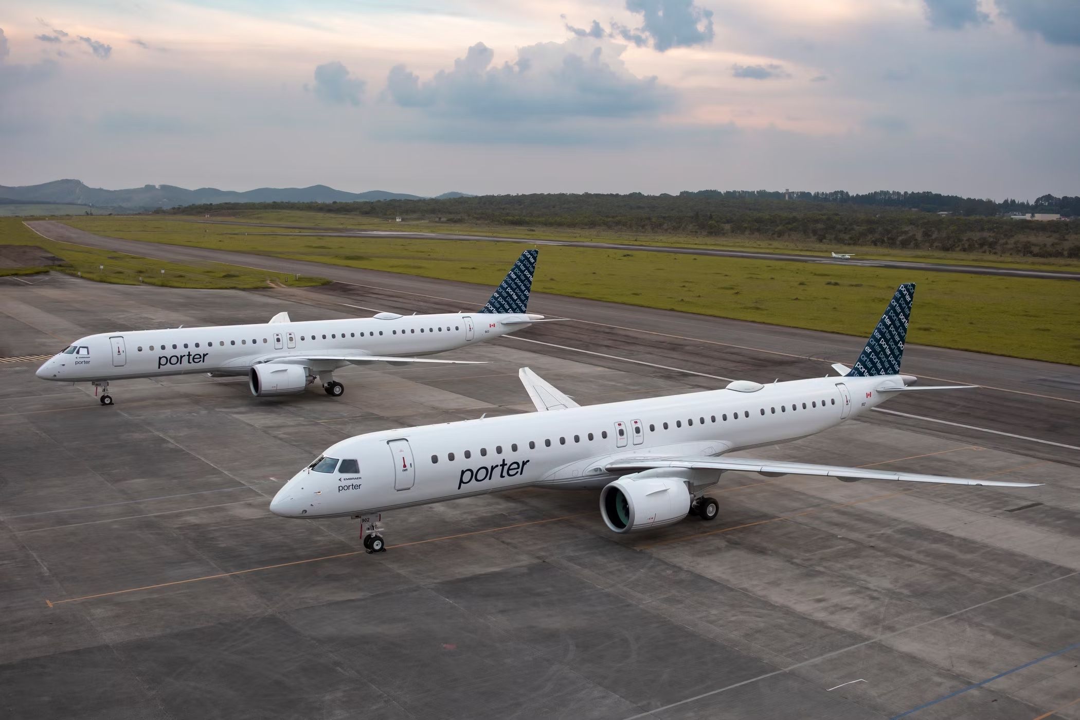 Two Porter Airlines Embraer jets on an airport apron.