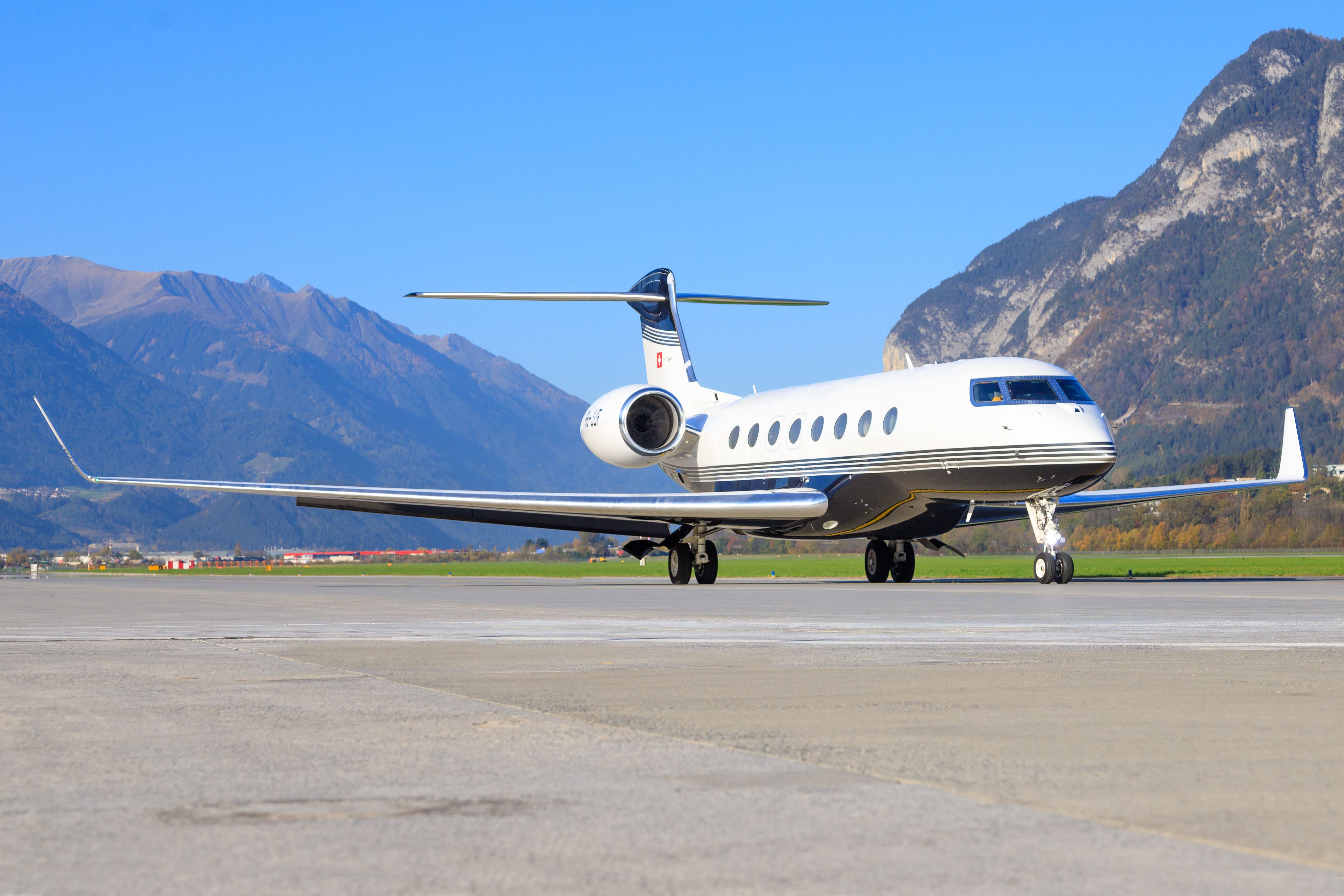 A Gulfstream G650 on an airport apron with mountains in the background.
