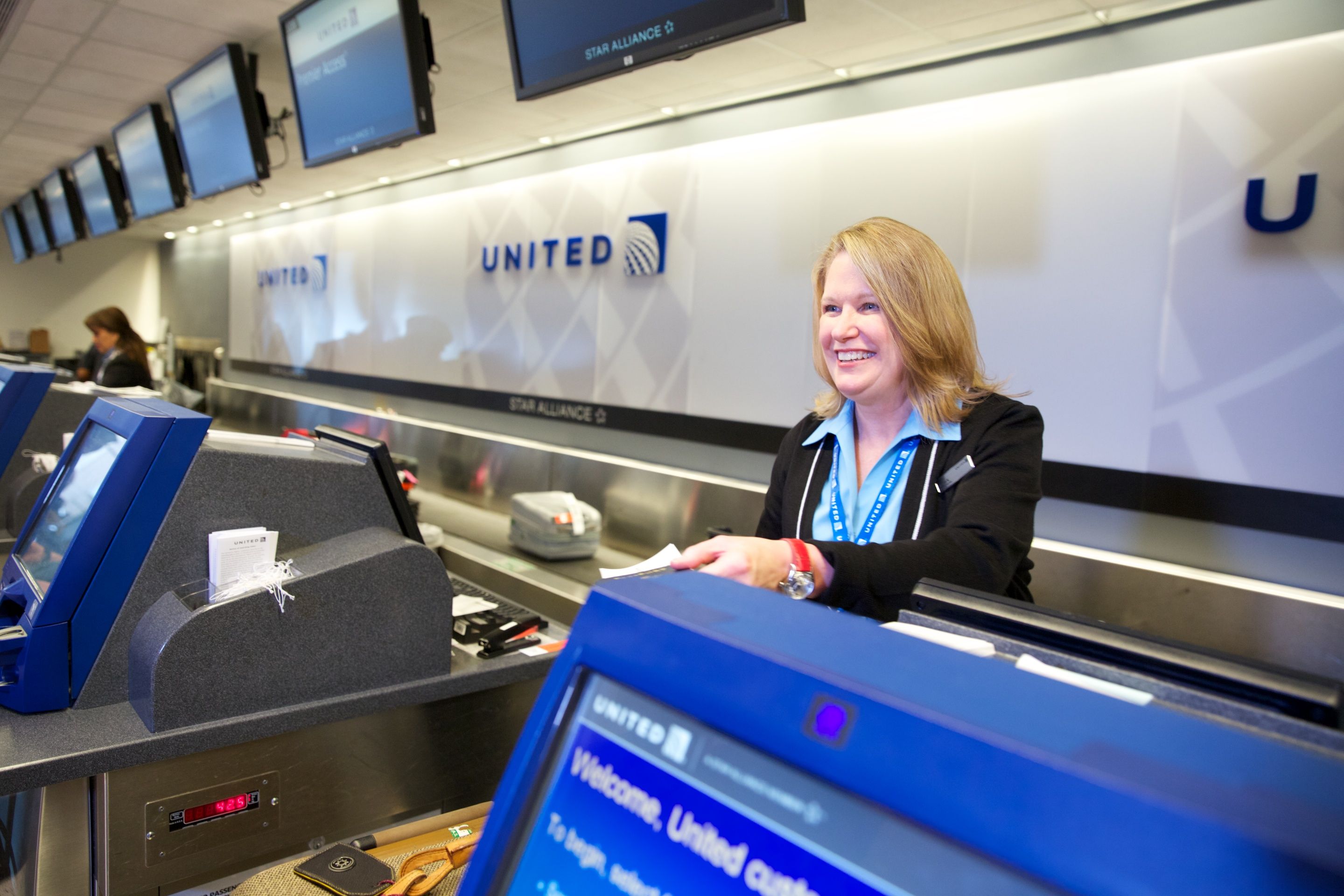 A Woman working at the United Airlines Check-in desk.