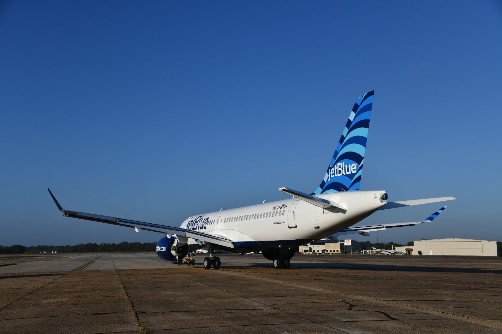 A JetBlue Airbus A220 parked at an airport