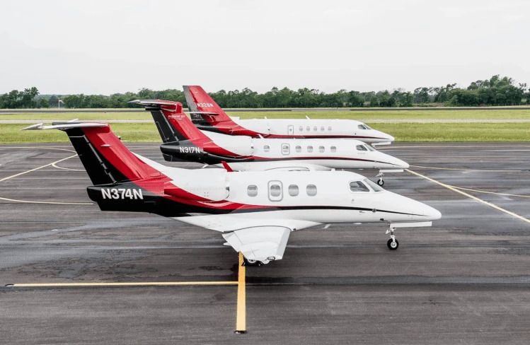 Three Nicholas Air Embraer Phenom 100 and Phenom 300 aircraft parked side by side on an airport apron.