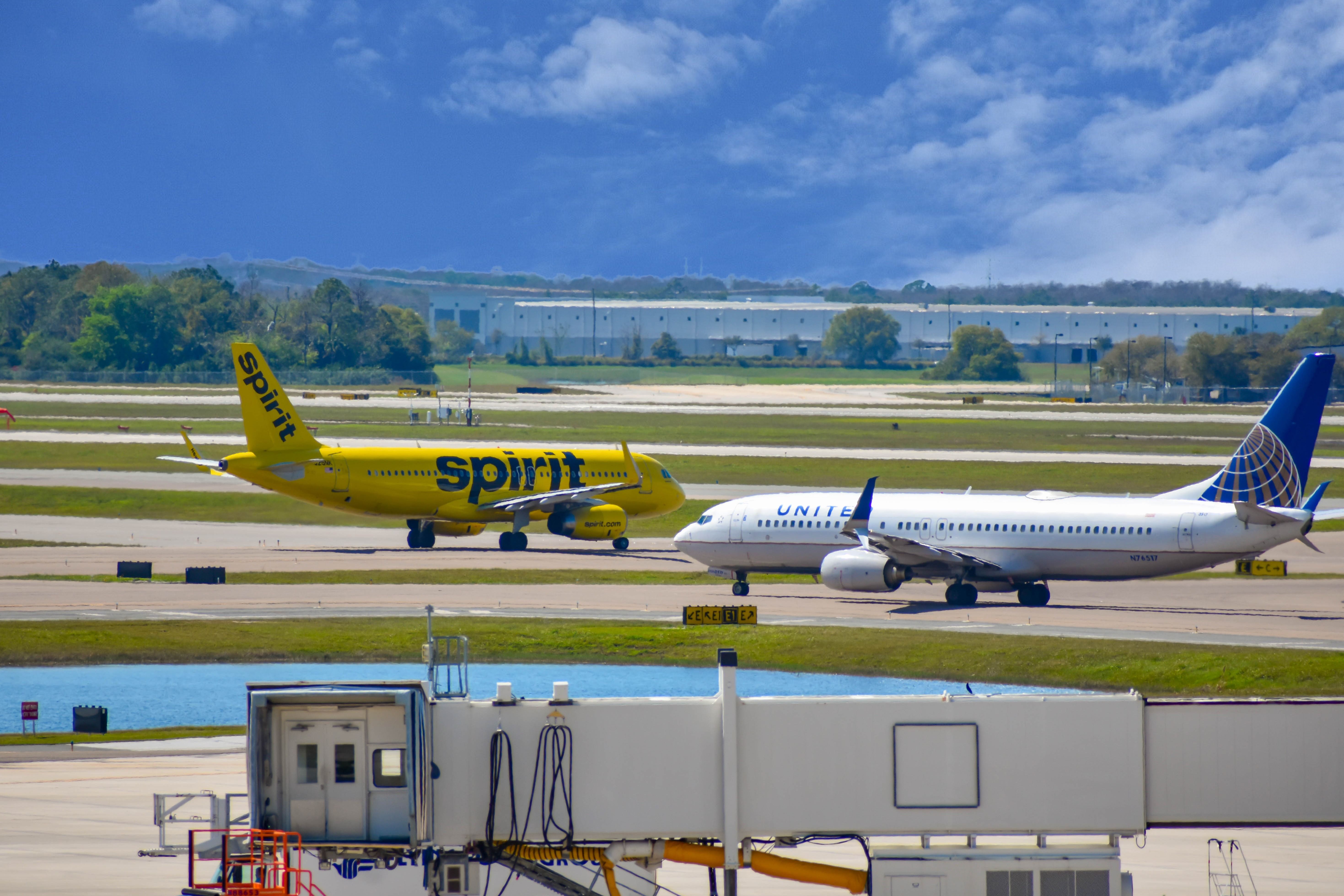 Spirit Airlines and United Airlines aircraft on runway preparing for departure from the Orlando International Airport.