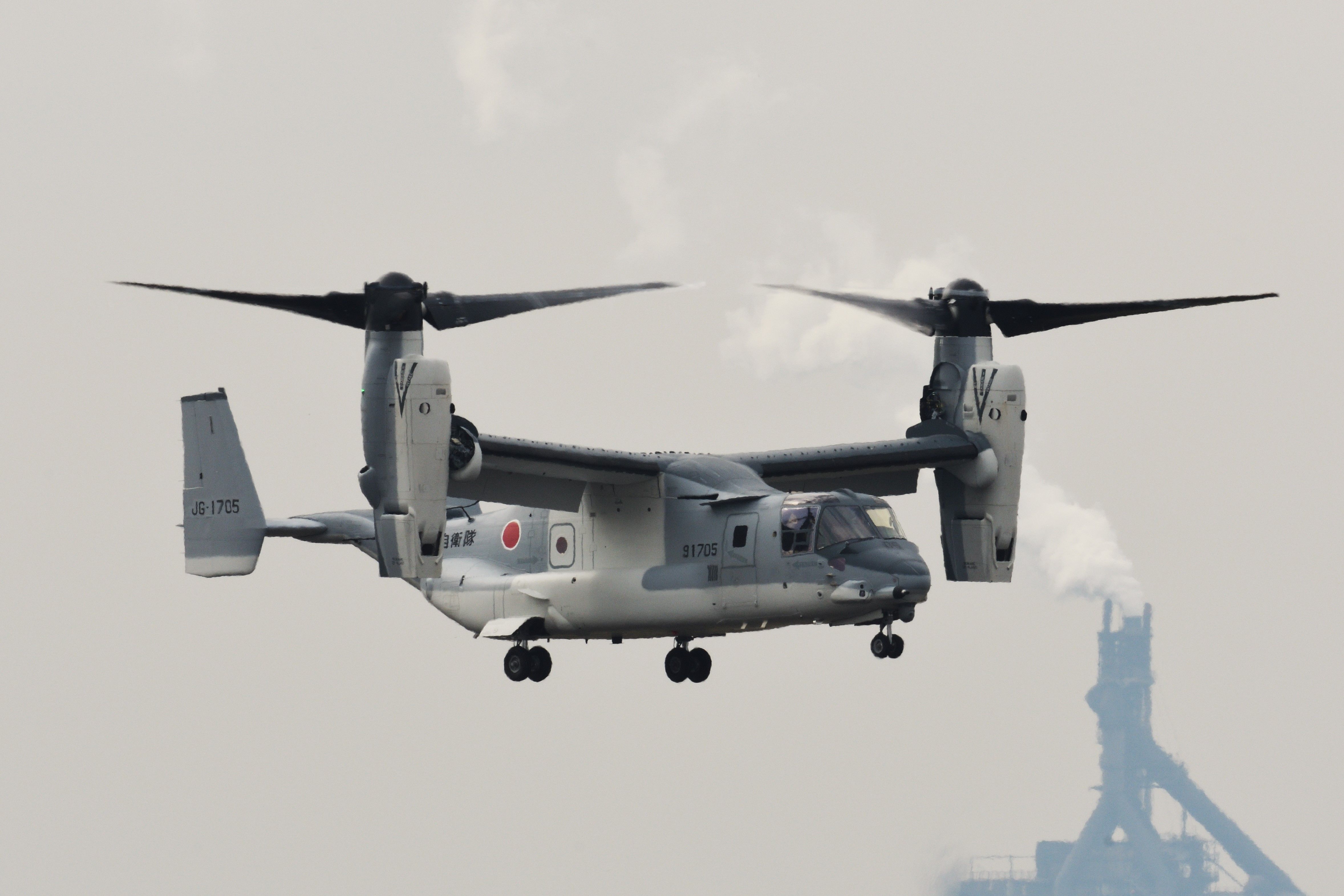 A Japan Ground Self-Defense Force Bell Boeing V-22 Osprey tiltrotor military transport aircraft hovering in the sky..