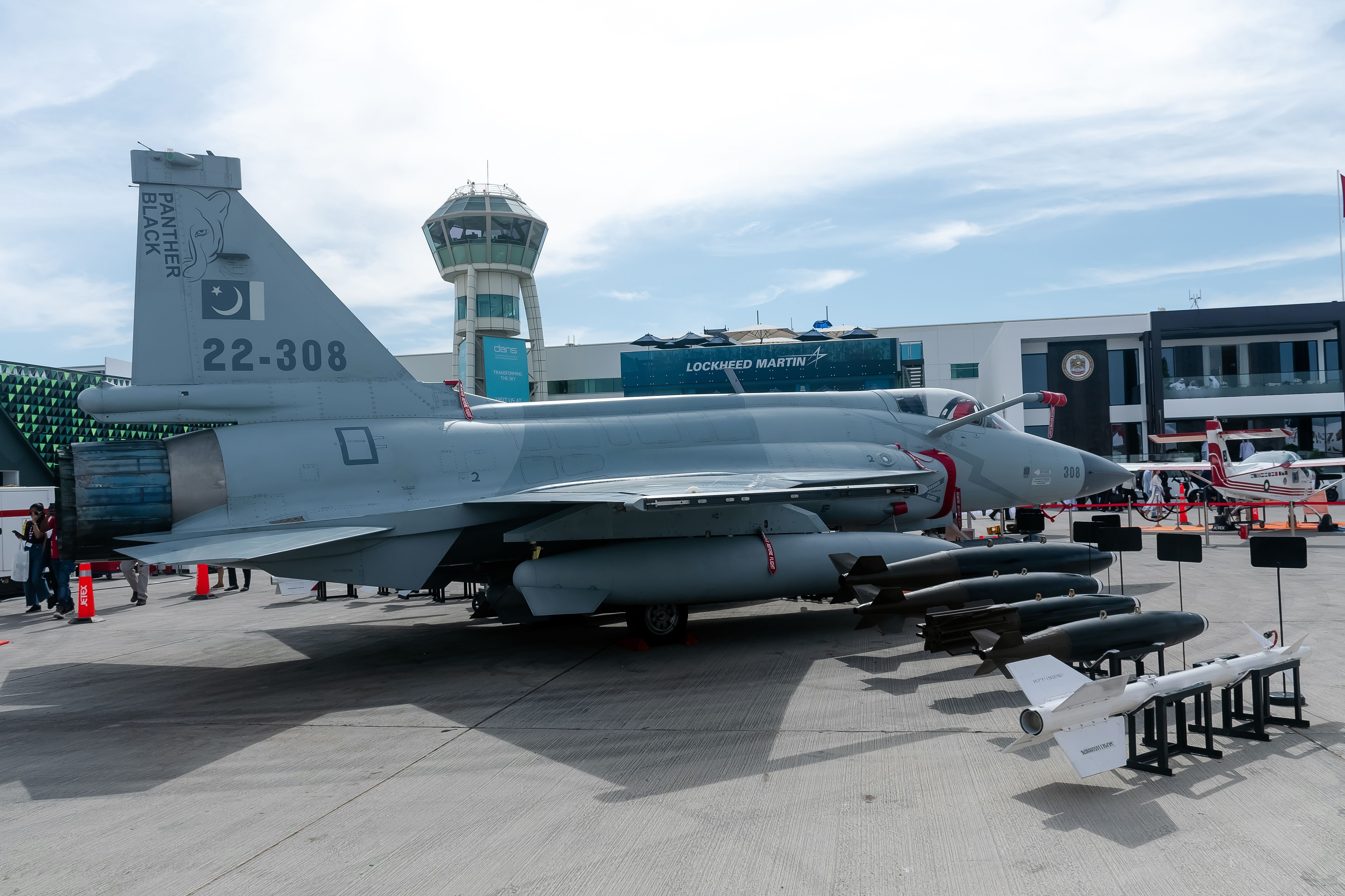 A PAF JF-17 surrounded by weapons on an airport apron.