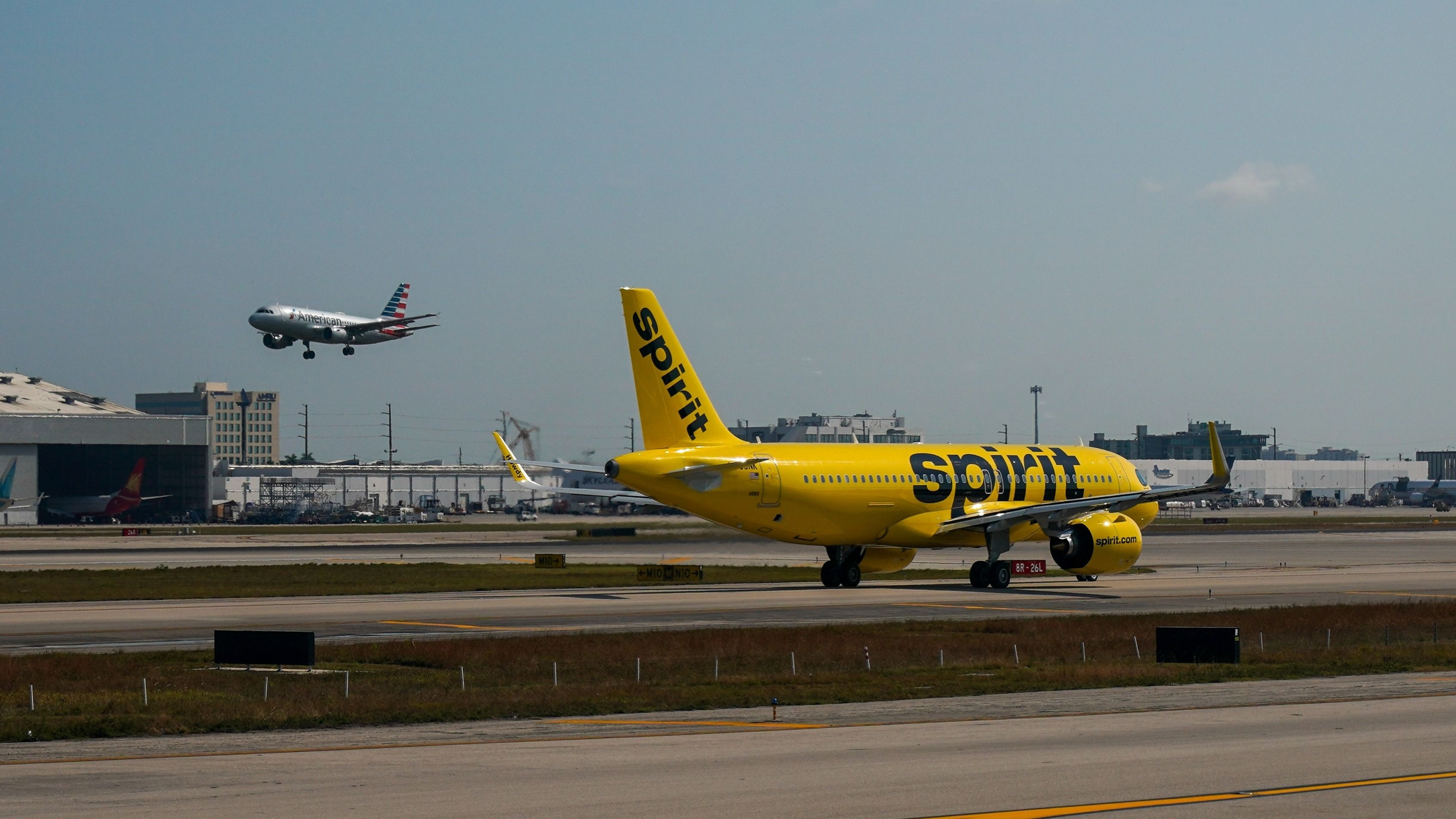 A Spirit Airlines aircraft on the apron at Miami International Airport as an American Airlines aircraft comes in to land..