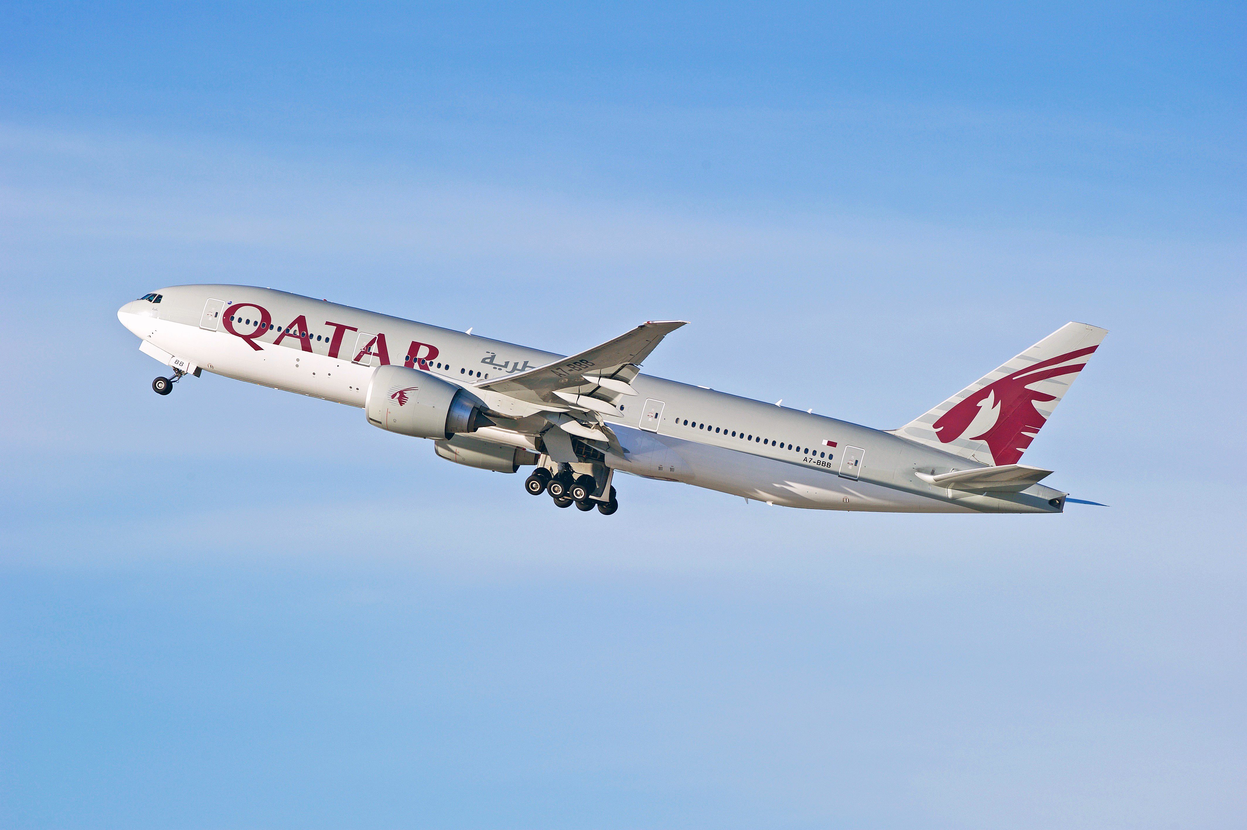 A Qatar Airways Boeing 777-200LR flying in the sky.