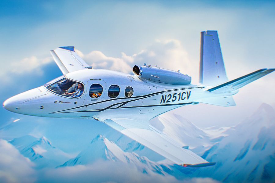 A Cirrus vision jet flying over snow-capped mountains.