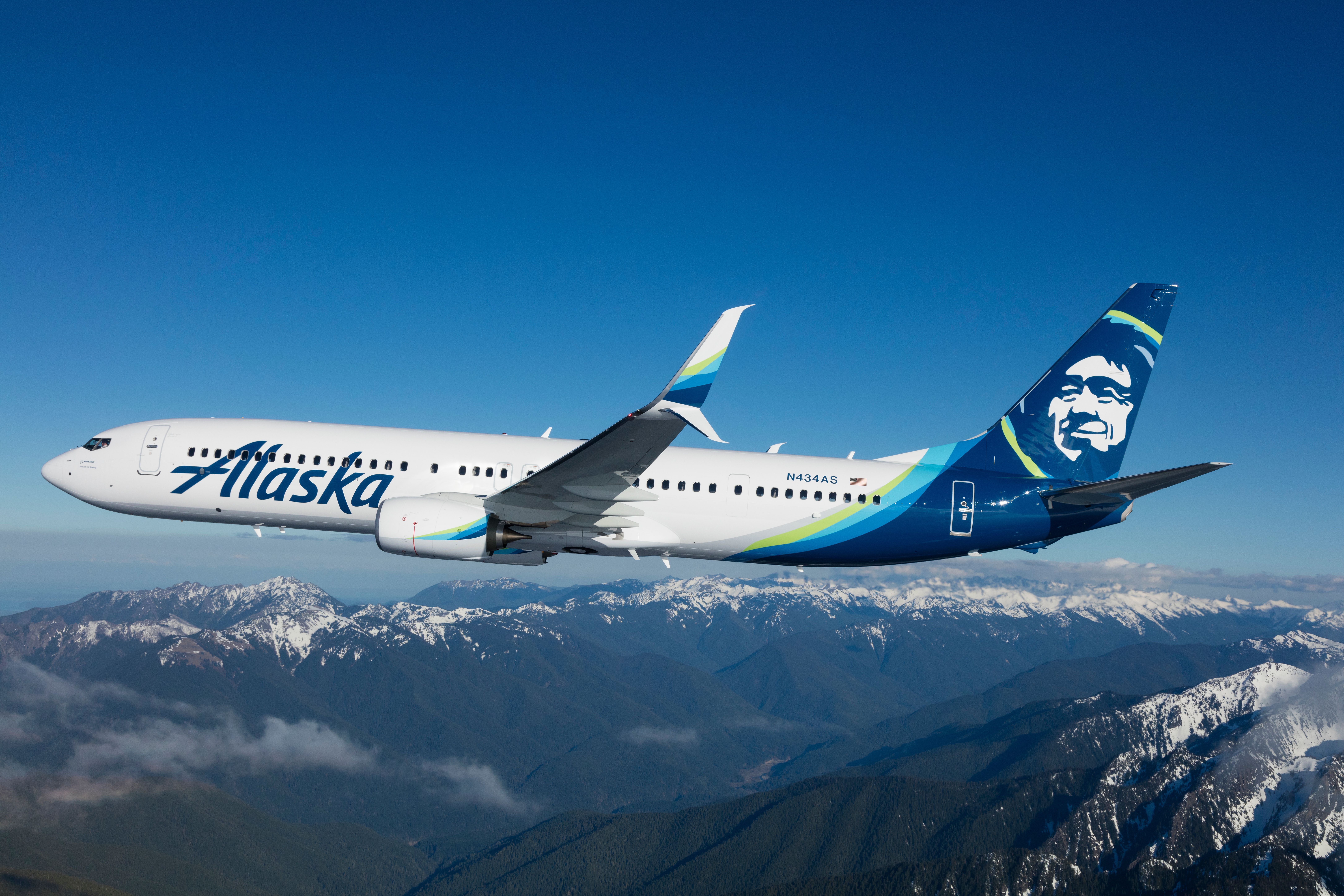 An Alaska Airlines Boeing 737-900ER Flying over mountainous terrain.