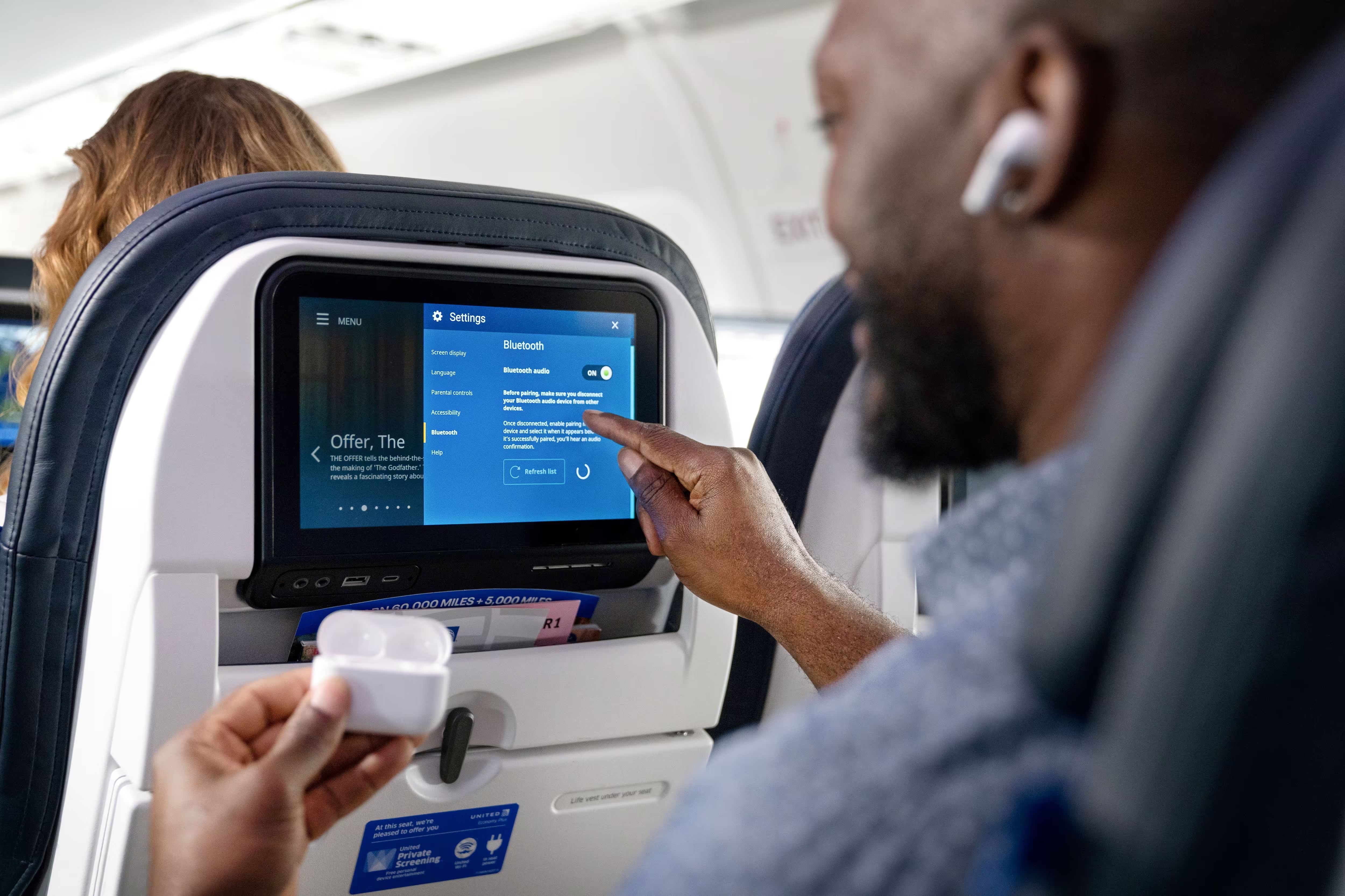 A passenger interacting with the United Airlines IFE screen.