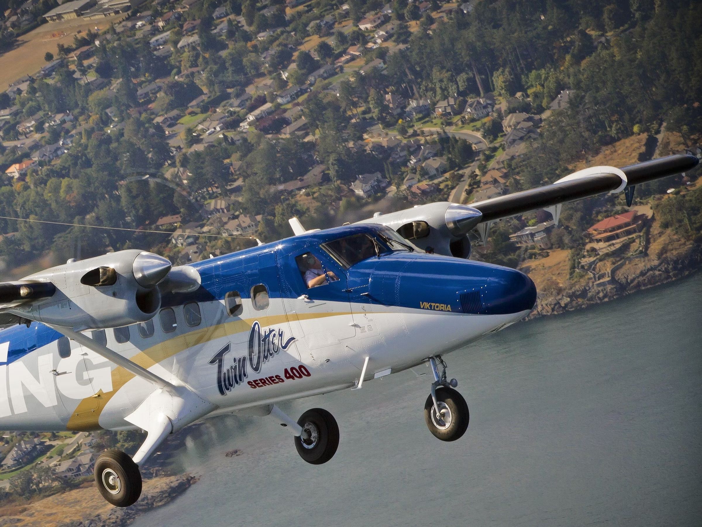 A Viking Air DHC-6 Twin otter flying over a lake.