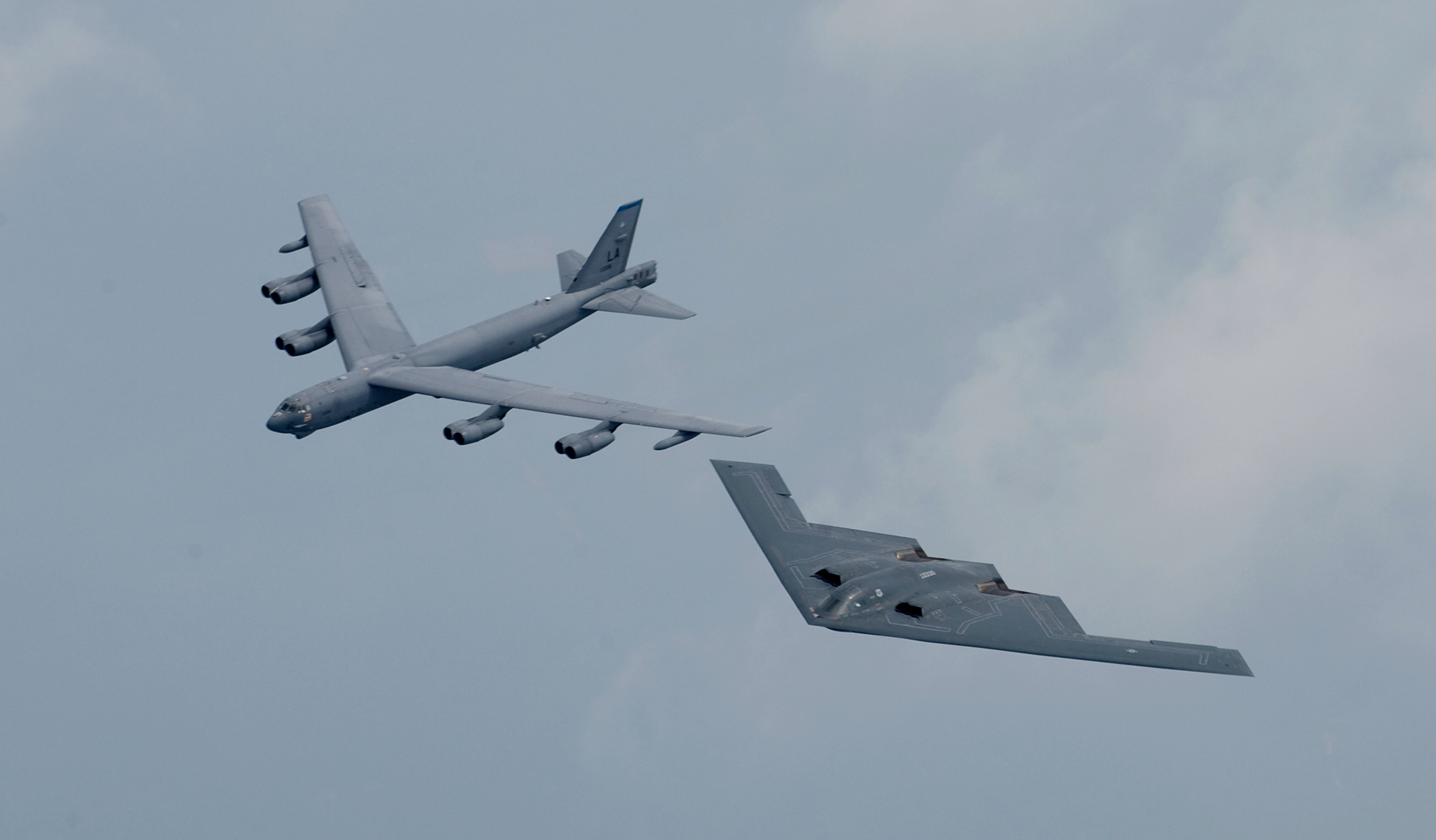A B-2 Spirit Bomber flying in formation with a B-52.