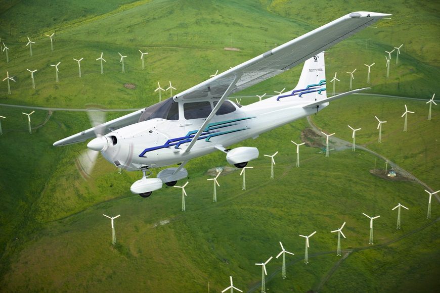 A Cessna 172 Skyhawk flying over a field filled with windmills.