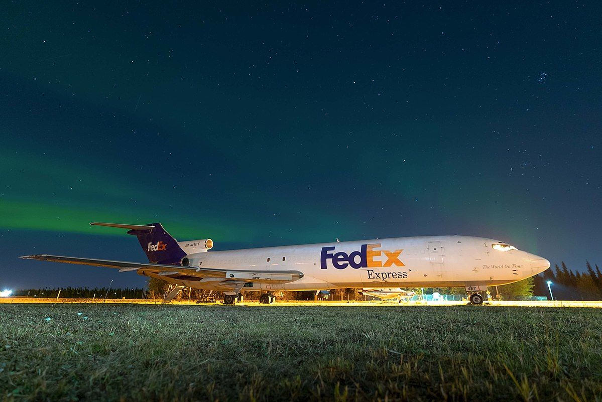A FedEx Boeing 727 parked on the apron at Fairbanks International Airport with Northern Lights in the sky..