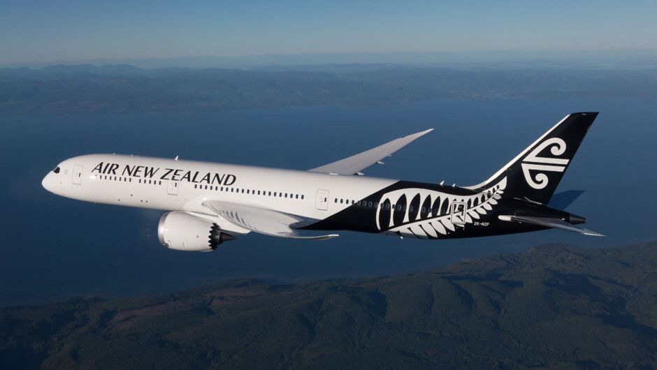 An Air New Zealand Boeing 787 Dreamliner flying over a coastal area.