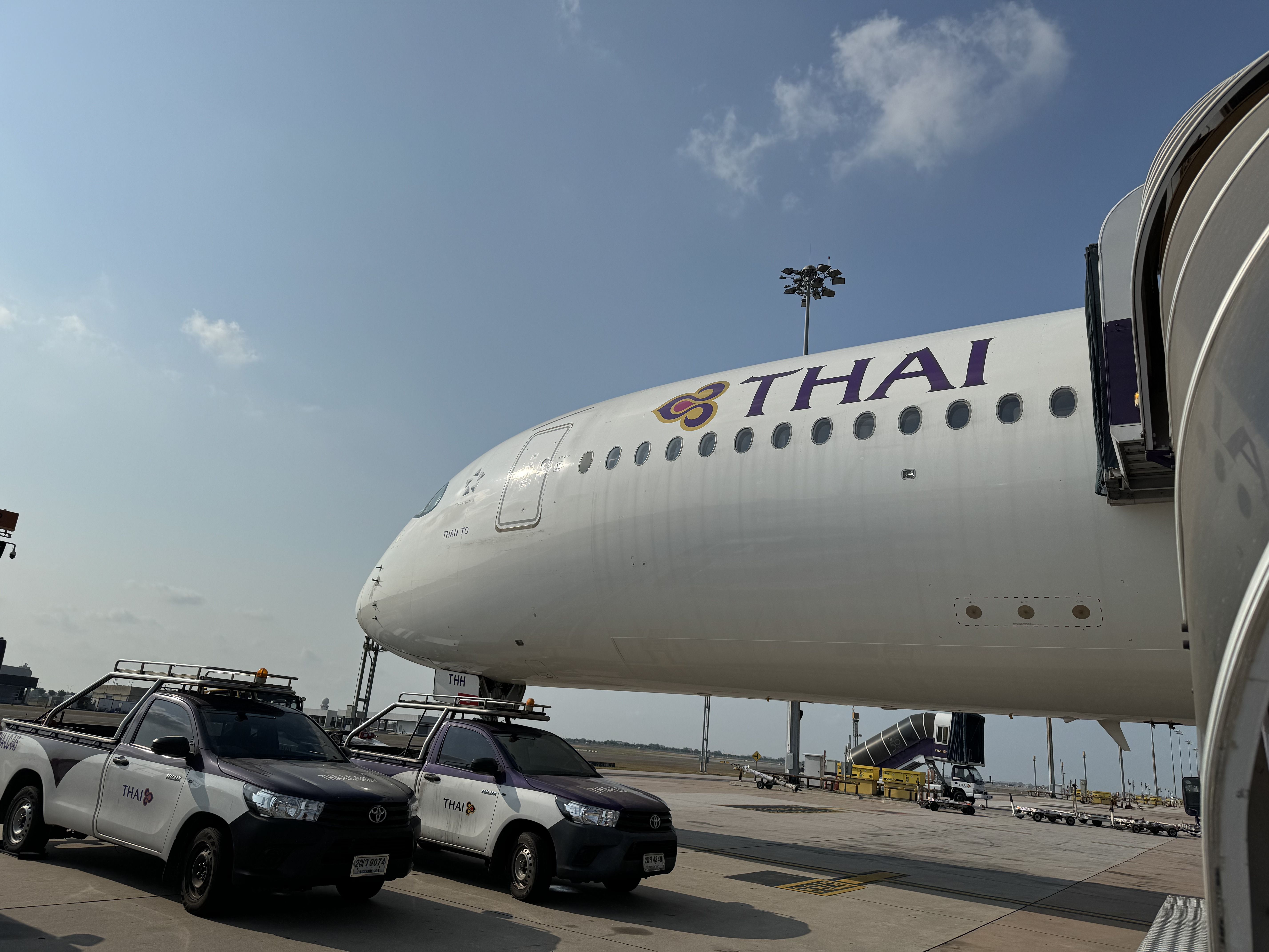 A Thai Airways Airbus A350 parked on an airport apron.