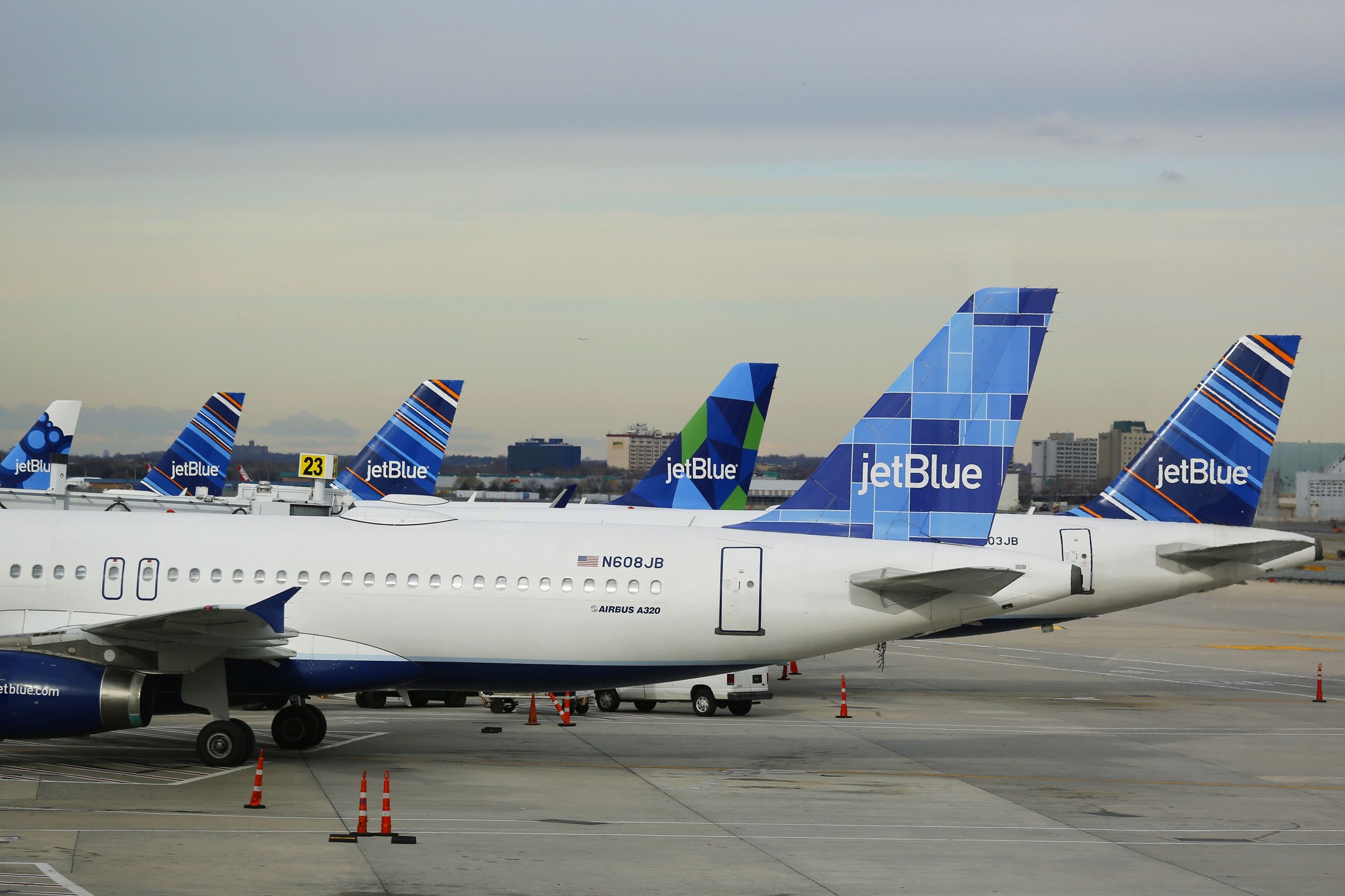 Several JetBlue Airbus A320 aircraft parked on the apron at gates at New York JFK Airport.