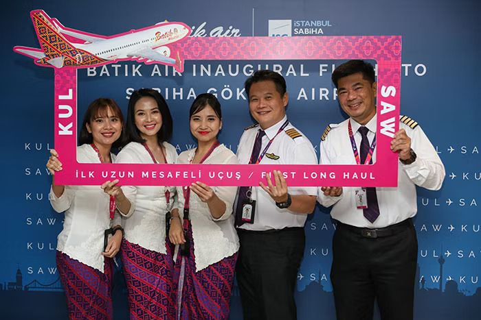 Five Batik Air employees holding up a sign commemorating their long haul service from Kuala Lumpur to Istanbul.