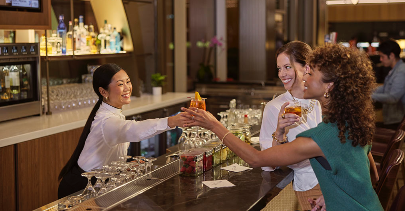 Two passengers getting drinks at the bar of a Delta Air Lines Sky Club lounge.