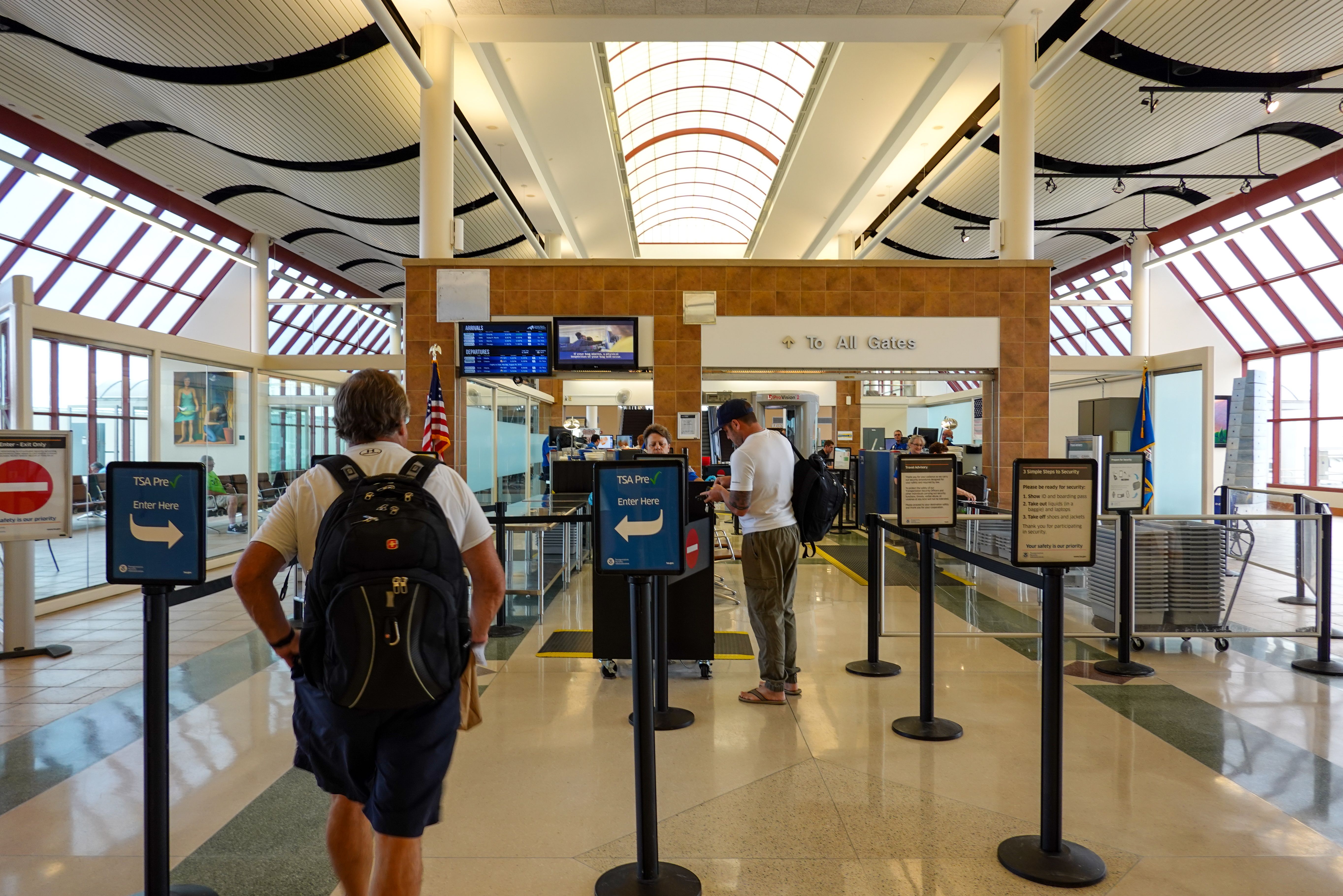Person going through TSA Precheck line and regular line through airport security.