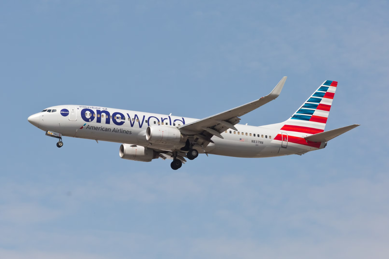 An American Airlines Boeing 737 in oneworld livery flying in the sky.
