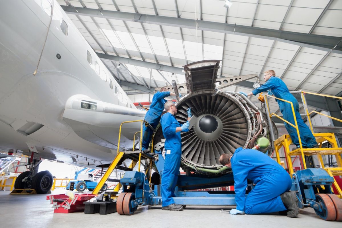 Engineers assembling an engine of a passenger jet at a hangar