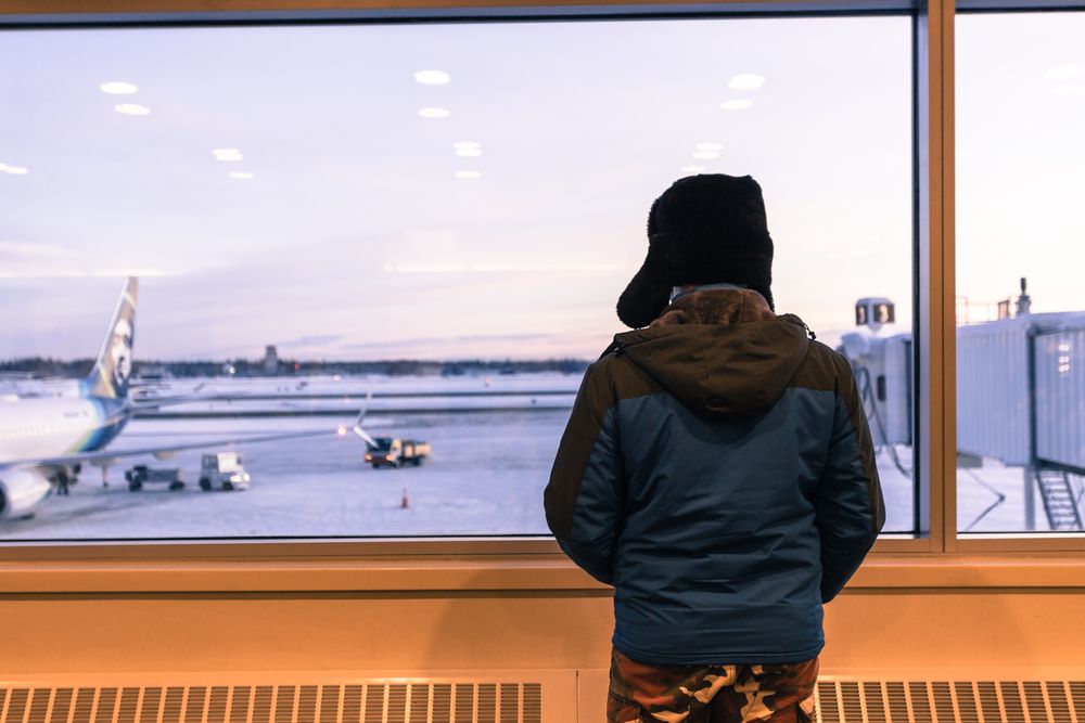 A Tourist looking out a terminal window at Fairbanks International Airport.