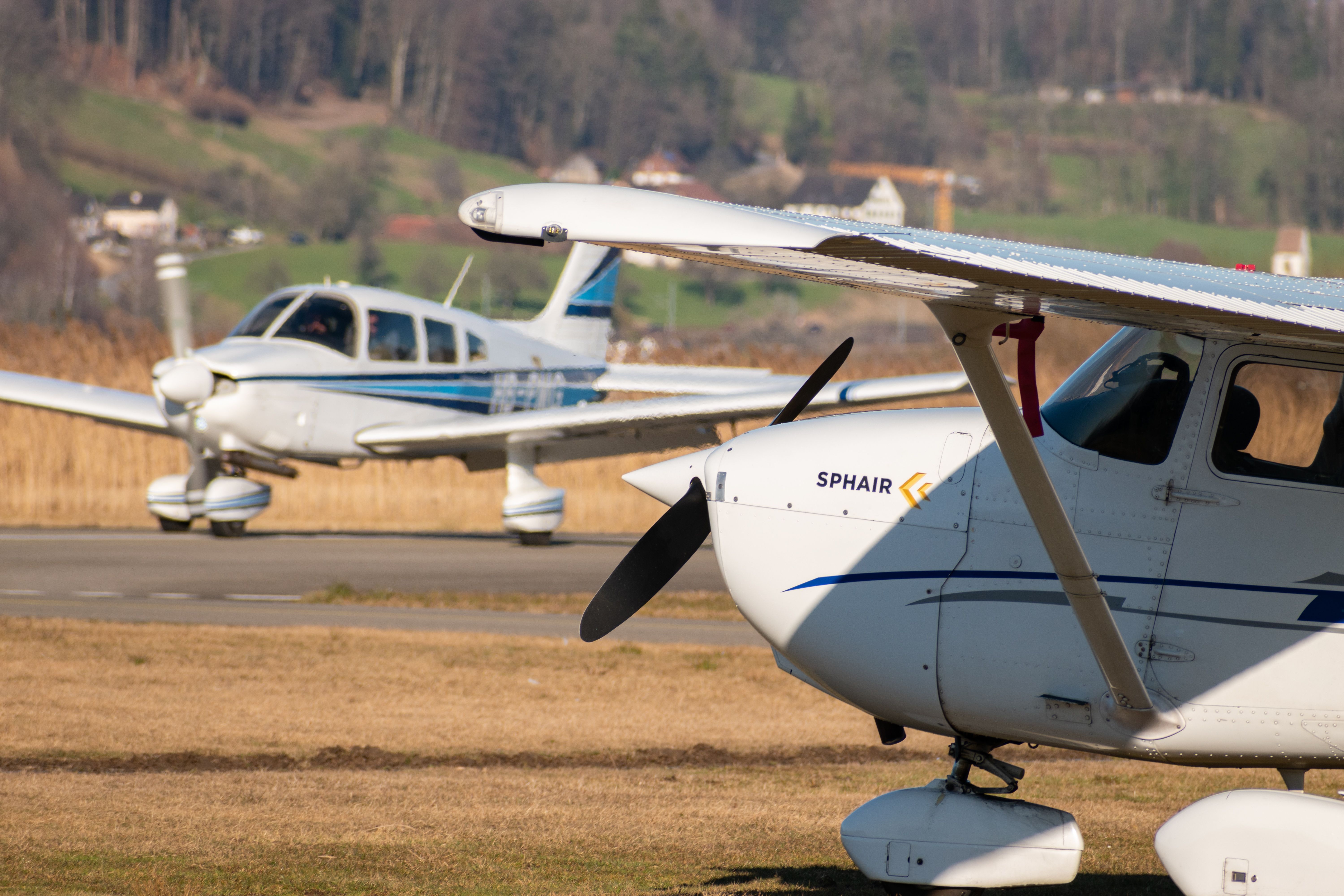 Cessna 172 and a Piper PA28-181 Archer II propeller plane at the parking area on a small airfield.