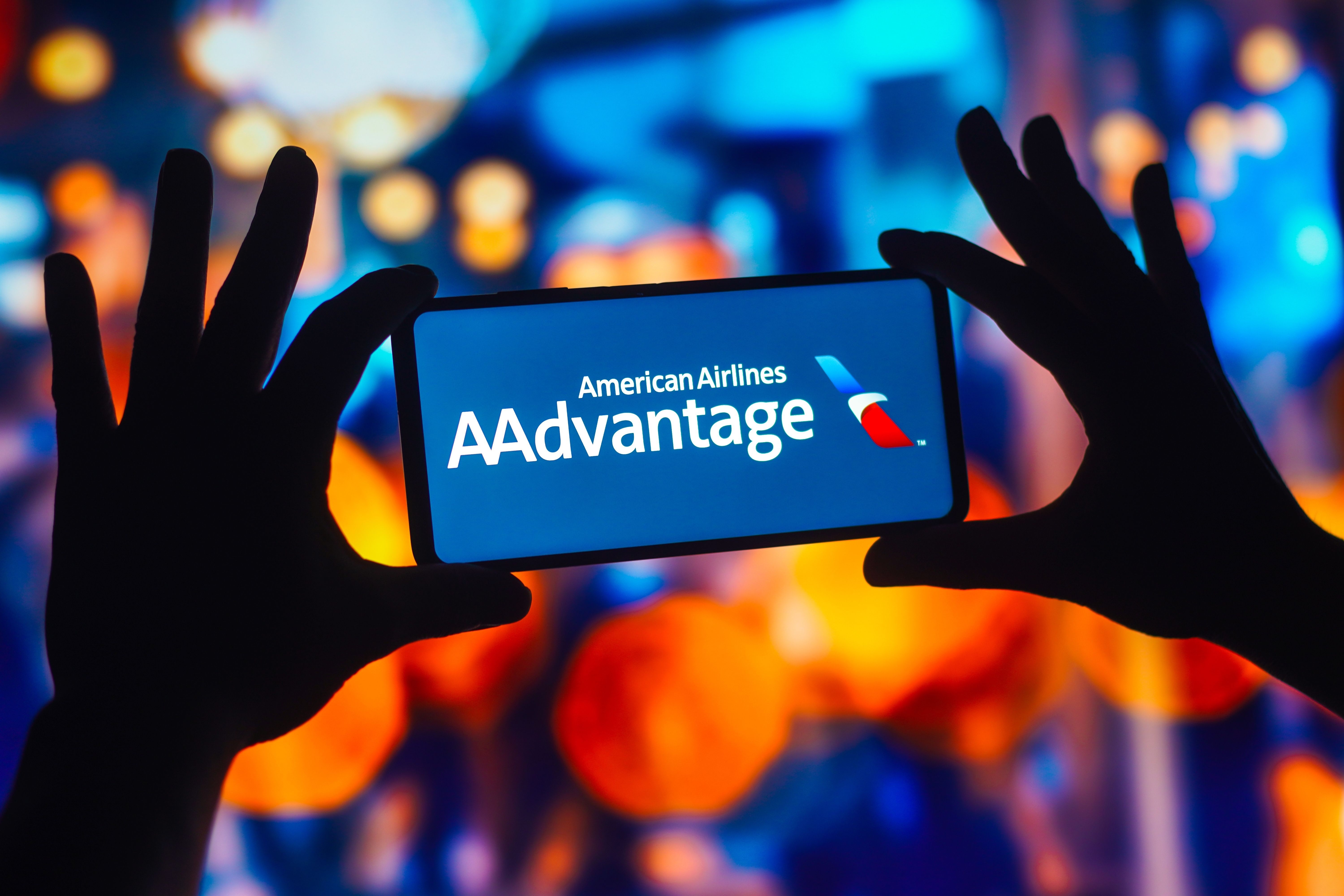 A person holds a cell phone with the American Airlines AAdvantage logo.