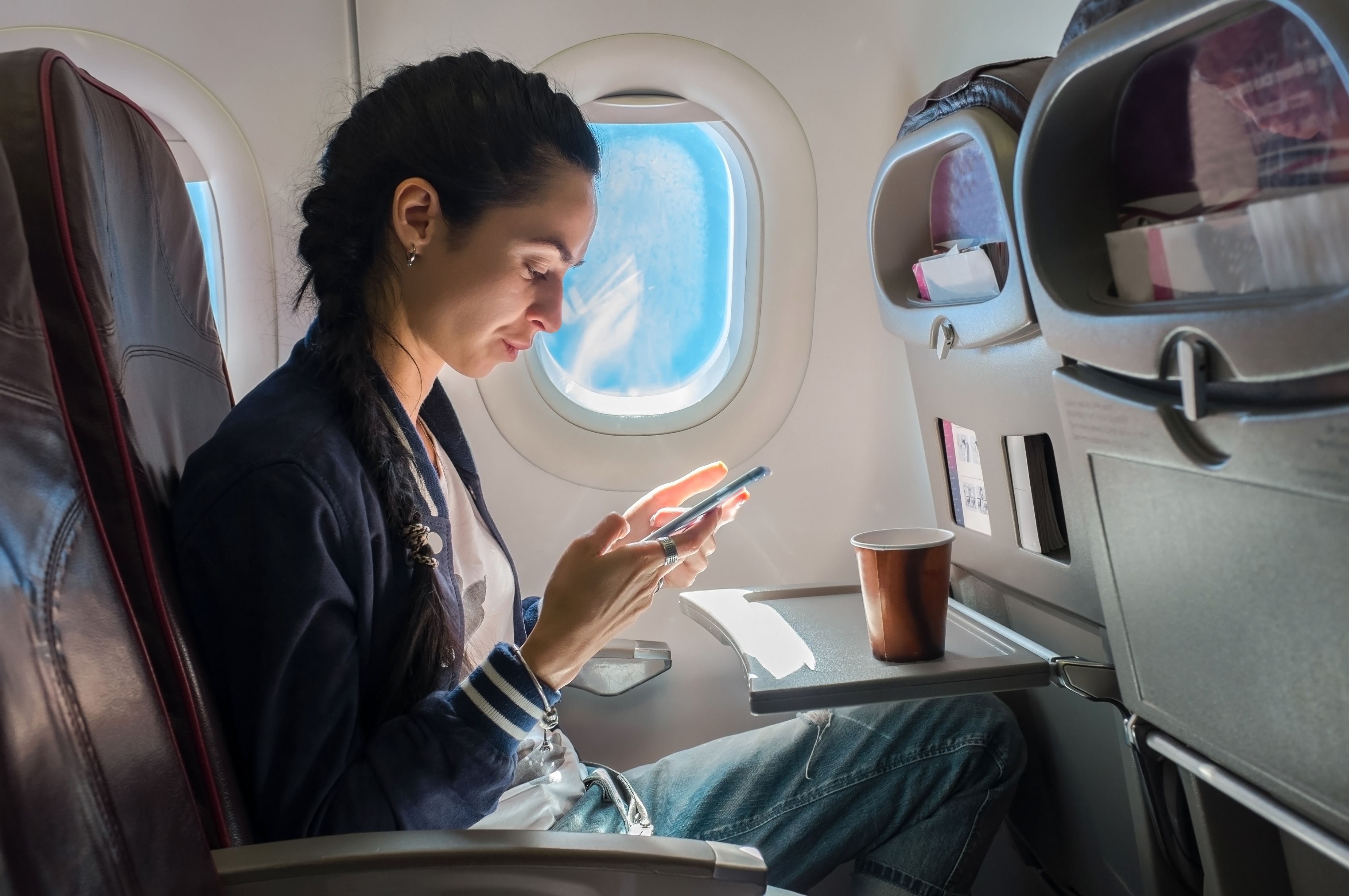 A passenger using a phone on a plane.