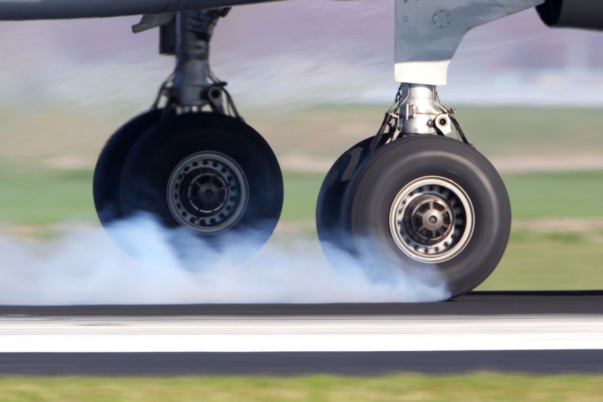 Airplane landing gear touching the runway with white smoke