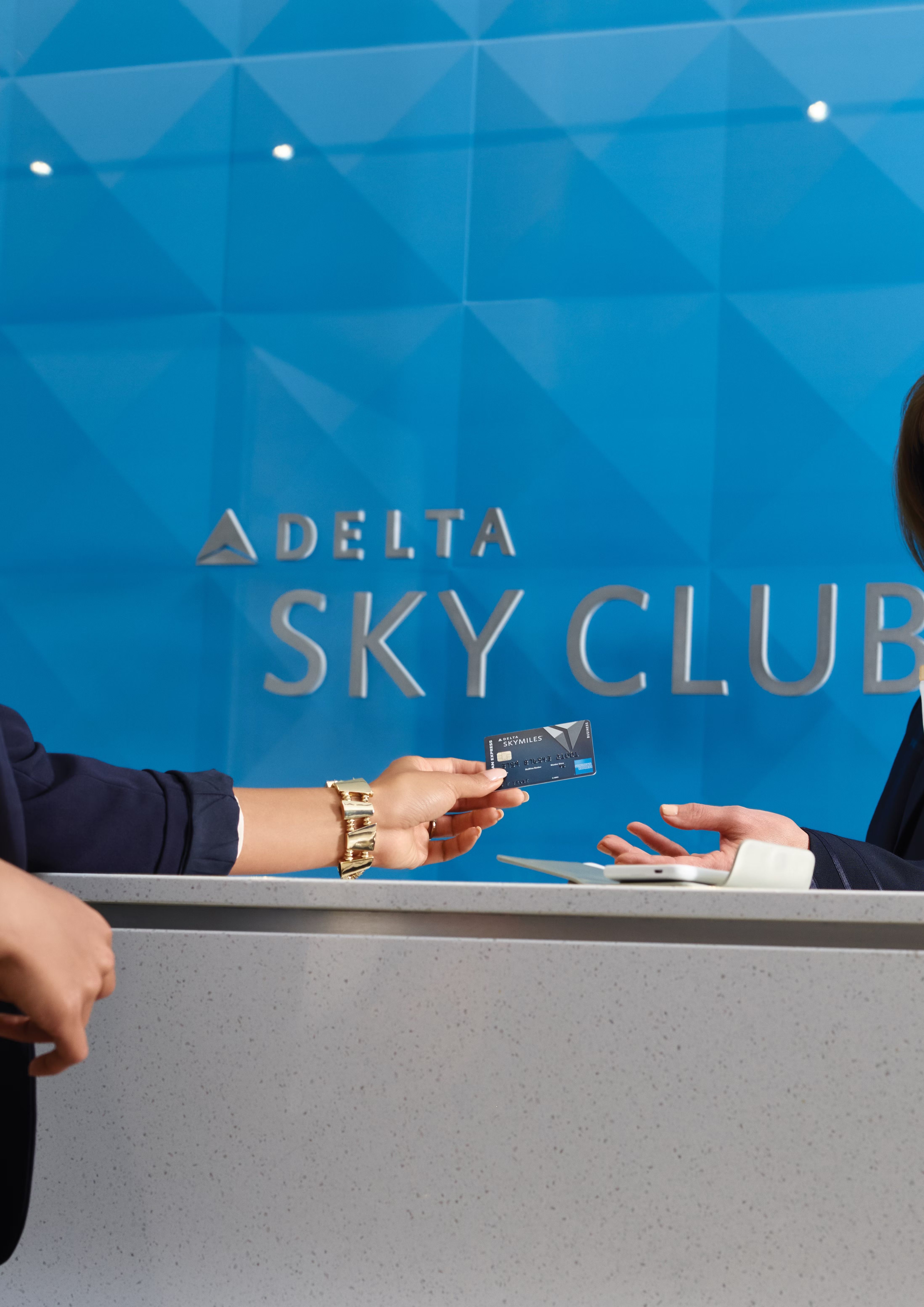 A Passenger showing a Delta Sky Club desk representative their Delta SkyMiles credit card.