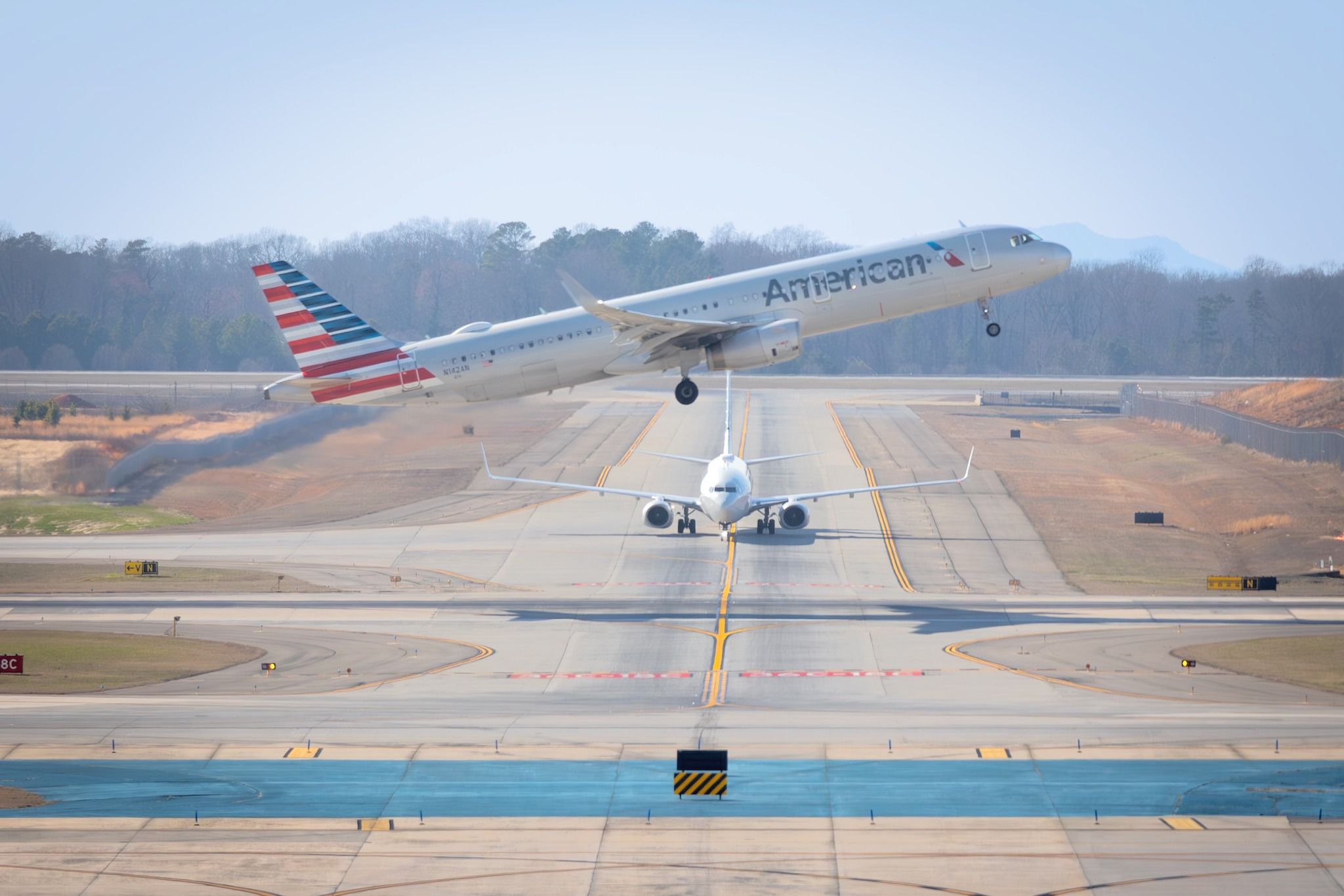 American Airlines Airbus A321 taking off with Boeing 737-823 in the background at Charlotte Douglas International Airport.