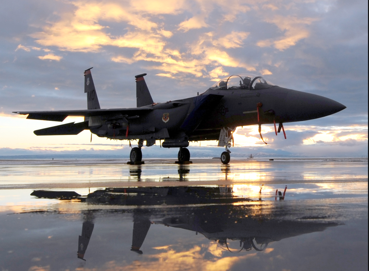 Image of an F-15 Eagle fighter aircraft reflecting on a wet flightline