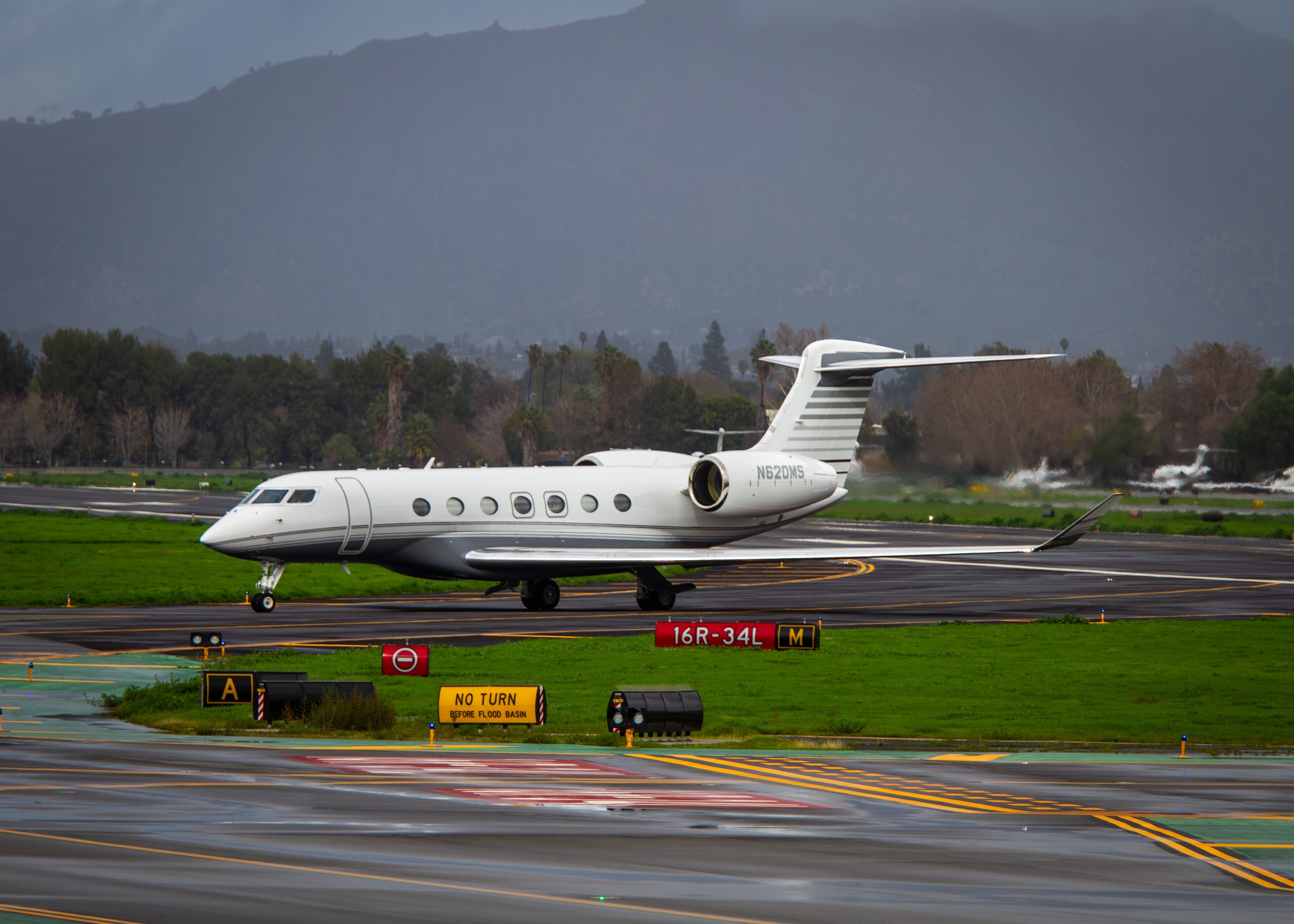 A Gulfstream 600 landing and clearing the a wet runway.