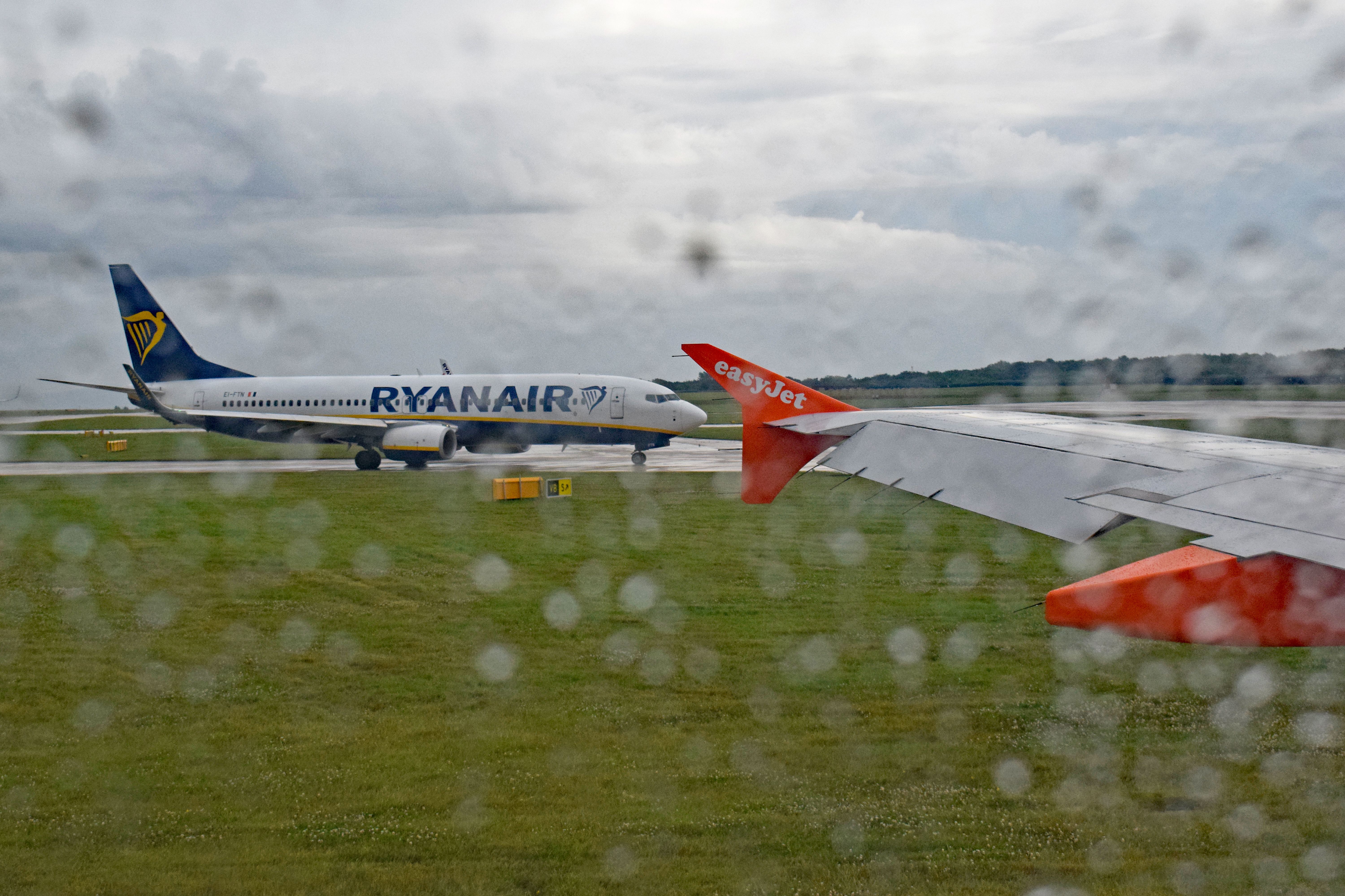 A Ryanair Boeing 737-800 visible from an easyJet Airbus aircraft at rainy Manchester Airport MAN shutterstock_1461029894