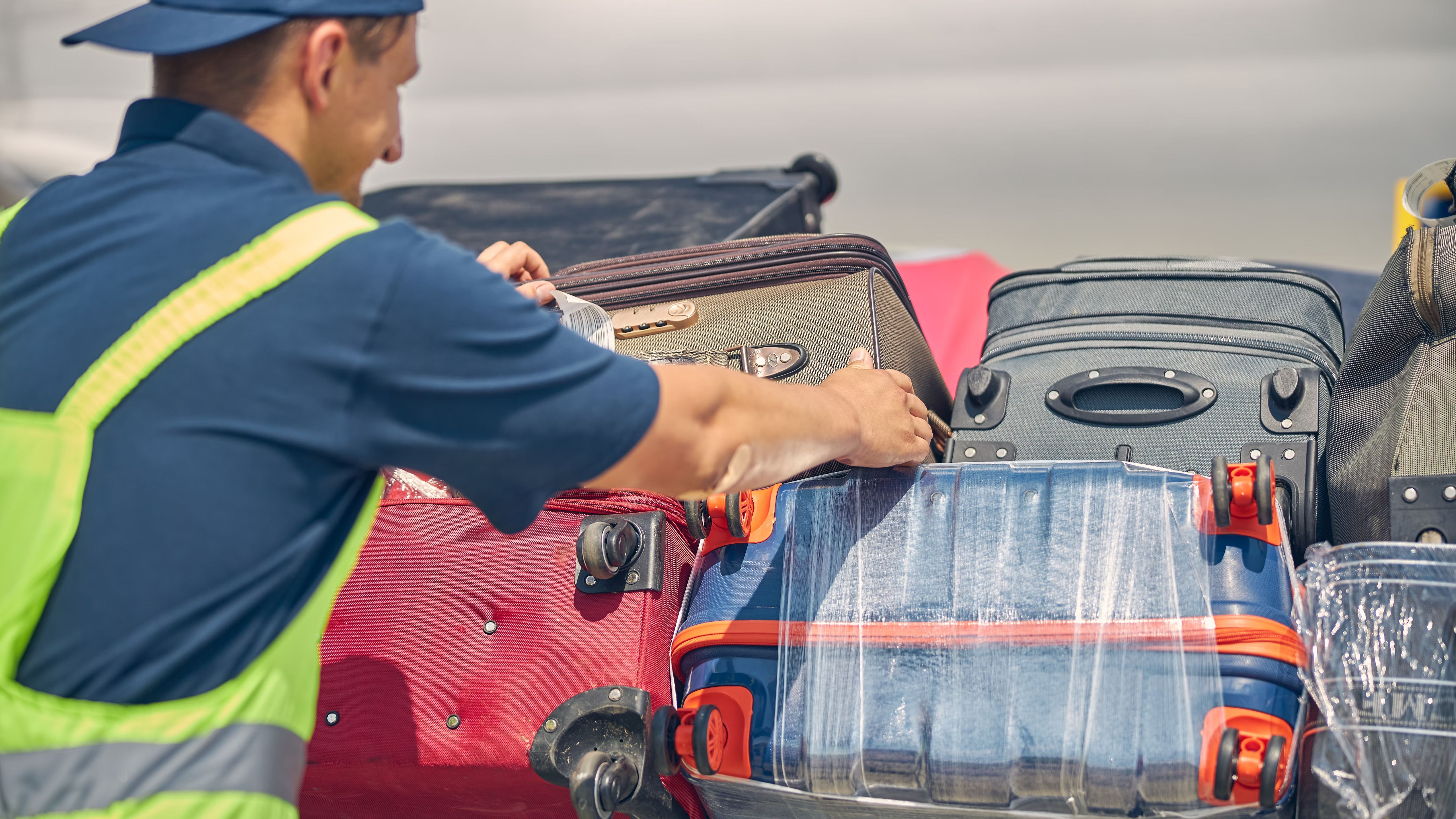 A Baggage handler moving luggage cases.