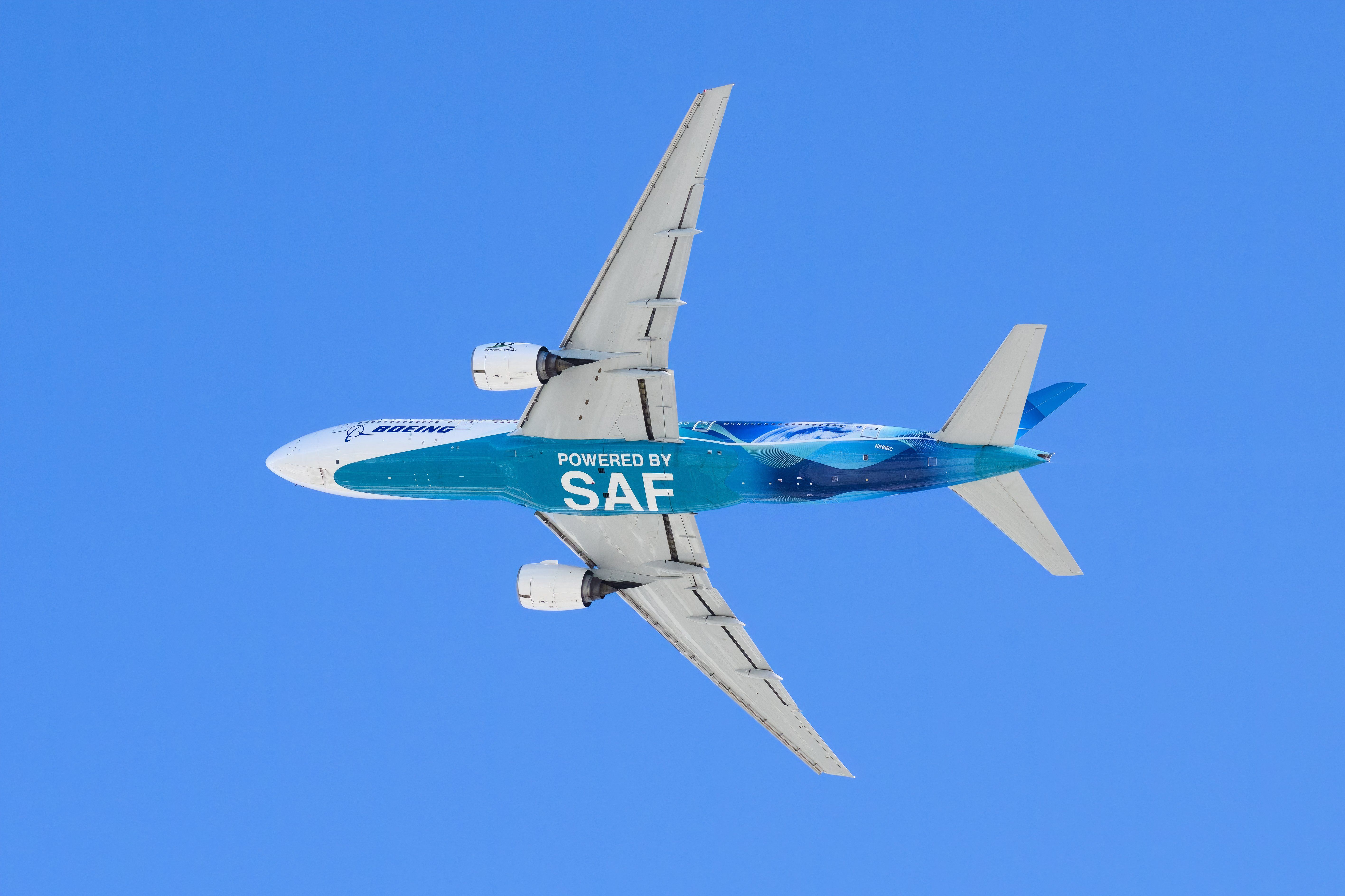 A Boeing 777 with the words "Powered by SAF Sustainable Aviation Fuel" on the underside