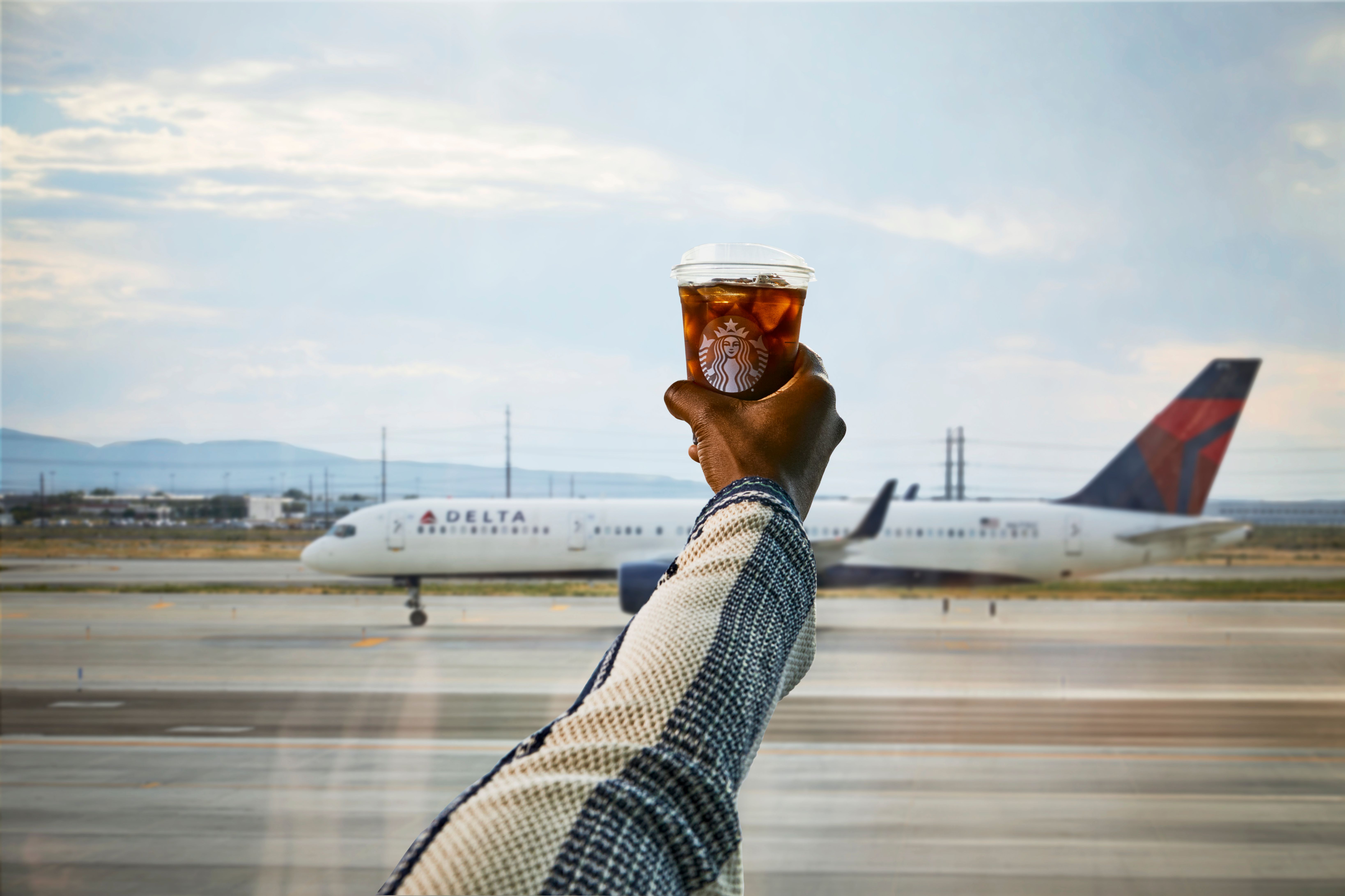 Starbucks drink with Delta Aircraft in background