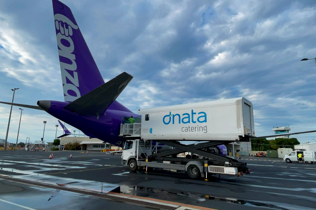 A dnata catering truck parked next to a Bonza aircraft.(thumbnail)