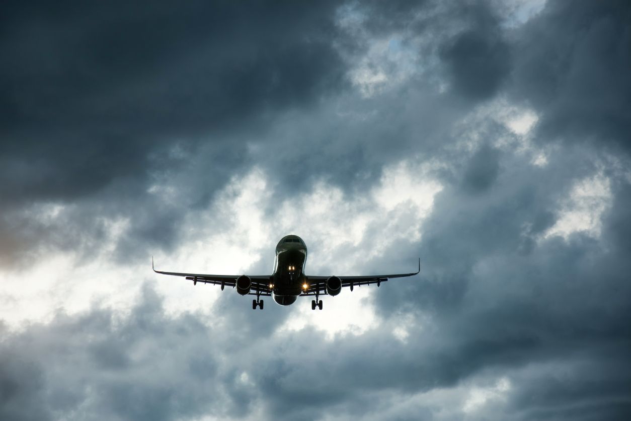 Airplane on approach with storm clouds in the distance.