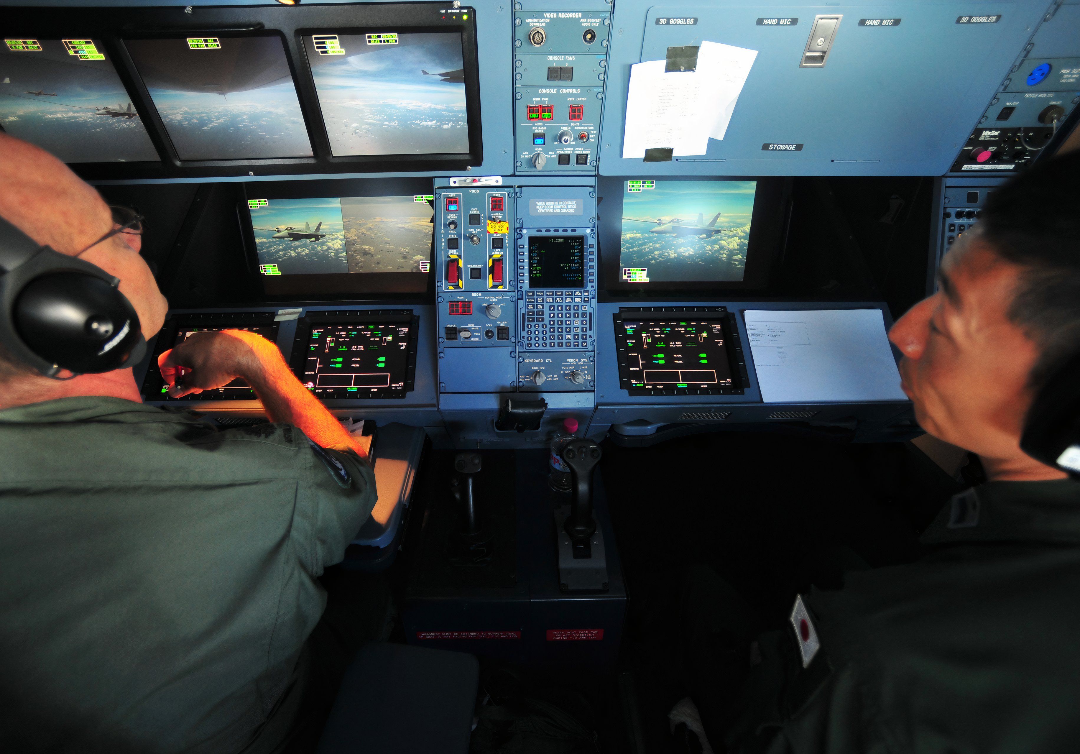 Crew members sitting at the aerial refueling console.