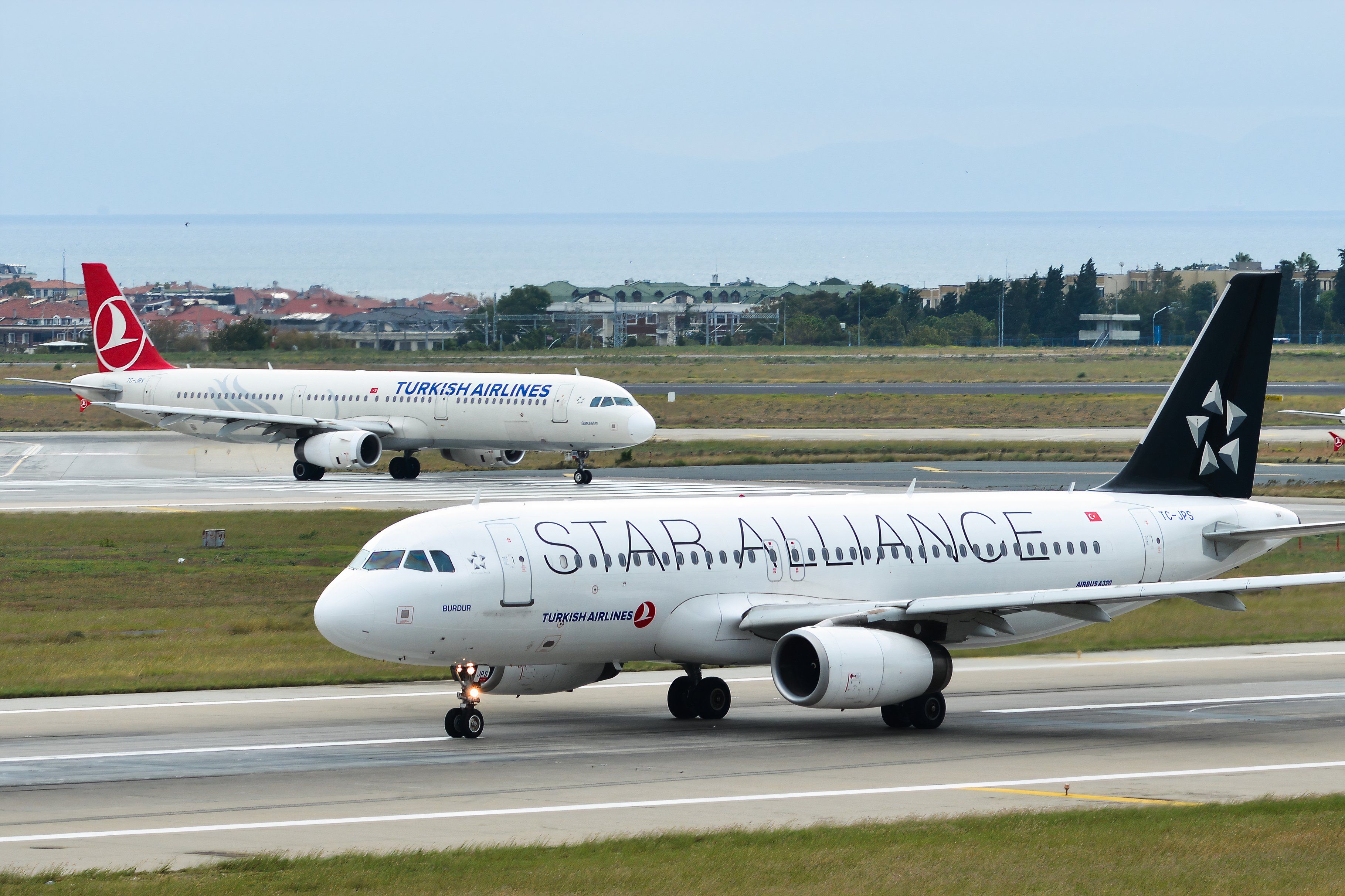 TC-JPS Turkish Airlines Airbus A320 (Star Alliance livery) taxiing on the runway of Istanbul Atatürk Airport (IST) next to an aircraft in the traditional livery