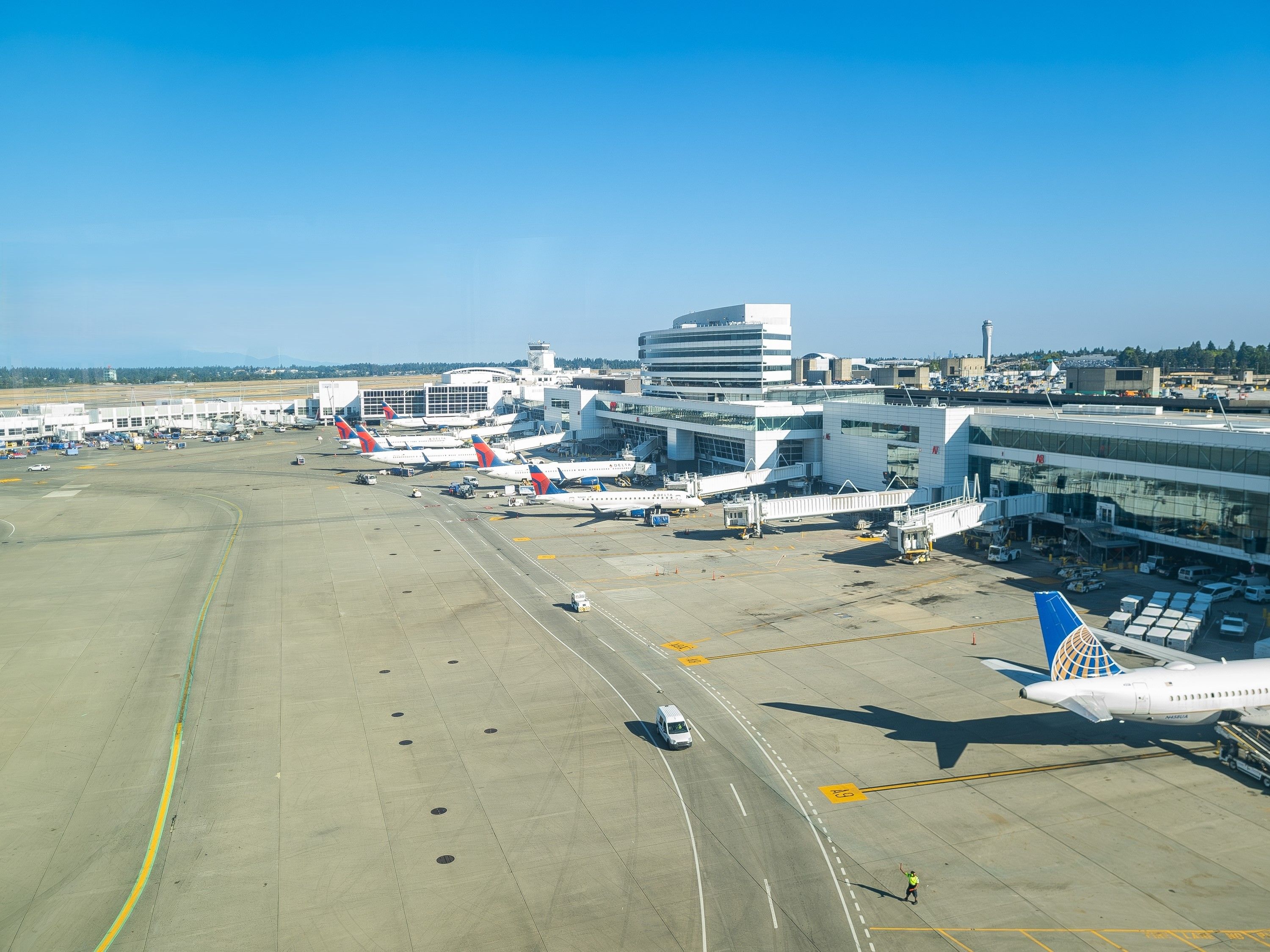     A view of Sea-Tec Seattle Tacoma International Airport from the international arrivals area on a clear summer morning with Delta and United aircraft visible and the tarmac