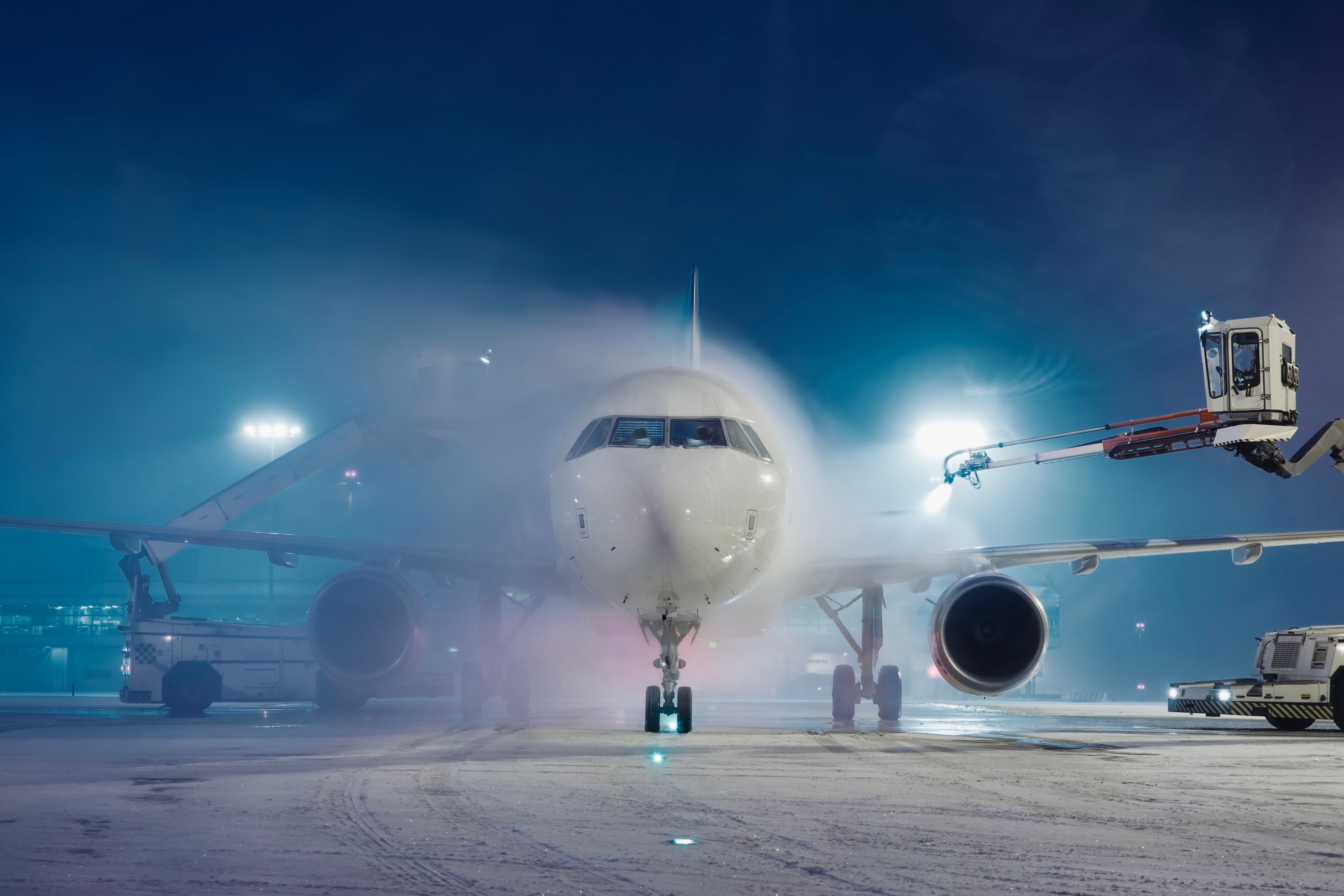 Deicing of airplane before flight. Winter frosty night and ground service at airport during snowfall.