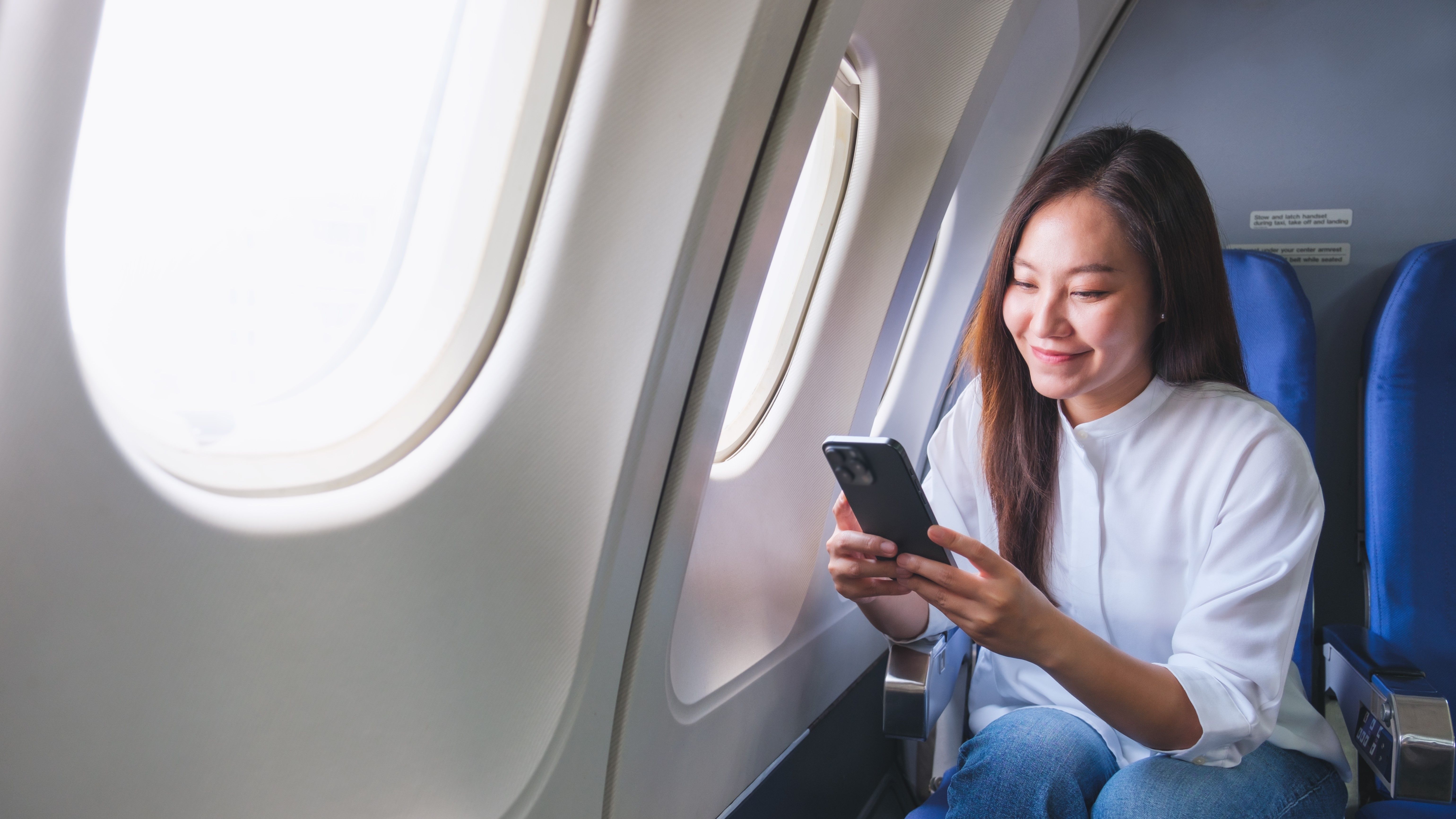 Woman using mobile phone on airplane